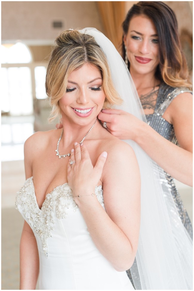 Maid of honor putting on brides necklace
