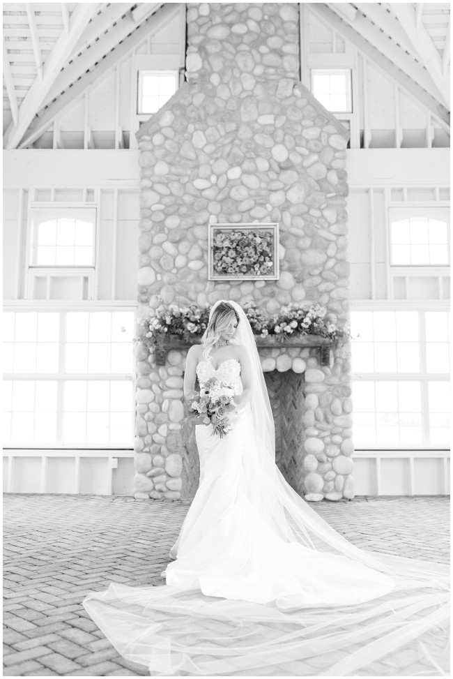 Black and white photo of bride in front of stone fireplace at Mallard Island Yacht Club