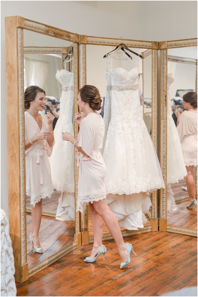 bride applying lipstick in mirror, bridal suite photos at excelsior