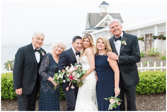 Bride and Groom with parents in front of the boathouse chapel at Mallard Island Yacht Club