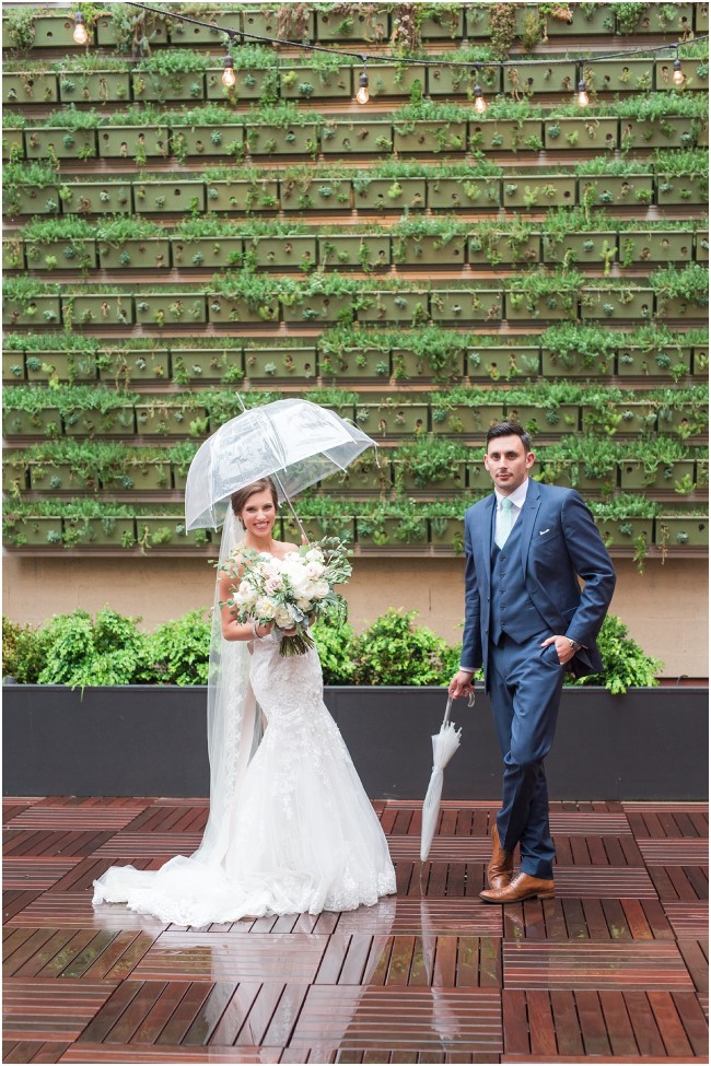industrial green planter wall outside excelsior in lancaster PA, bride and groom with umbrellas