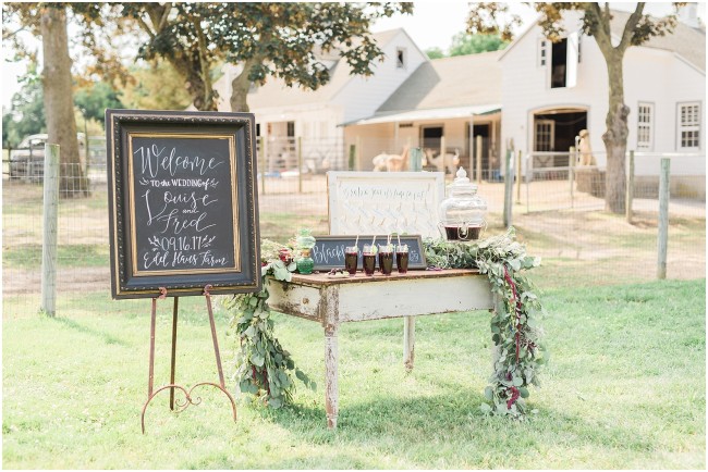 custom calligraphy brushed gold and black wedding signage, rustic alpaca farm wedding details, welcome table with beverages for wedding day