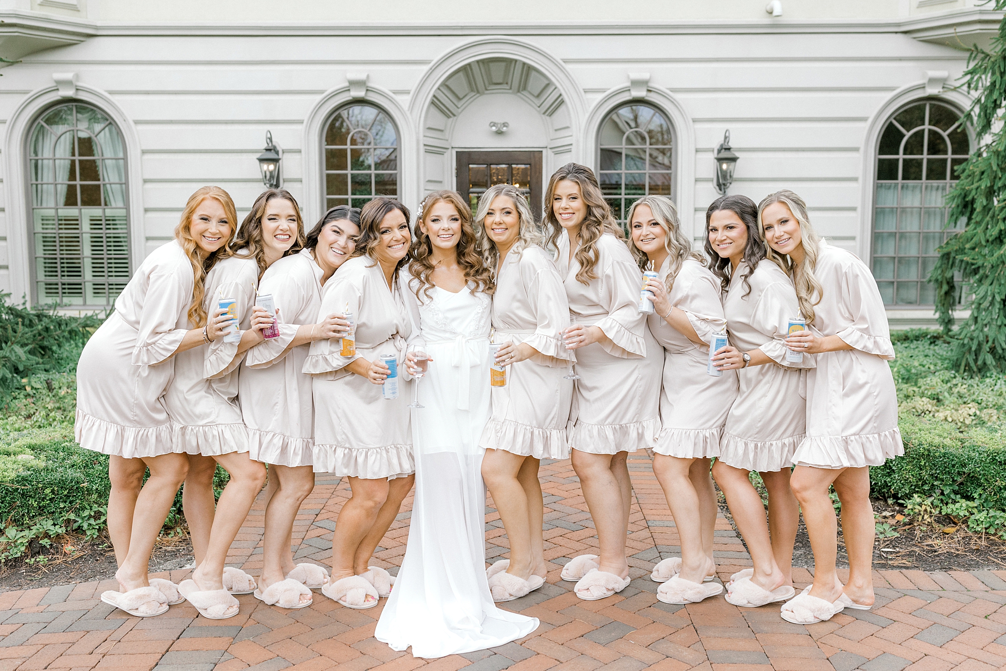 bride poses with bridesmaids in ivory robes outside Ashford Estate