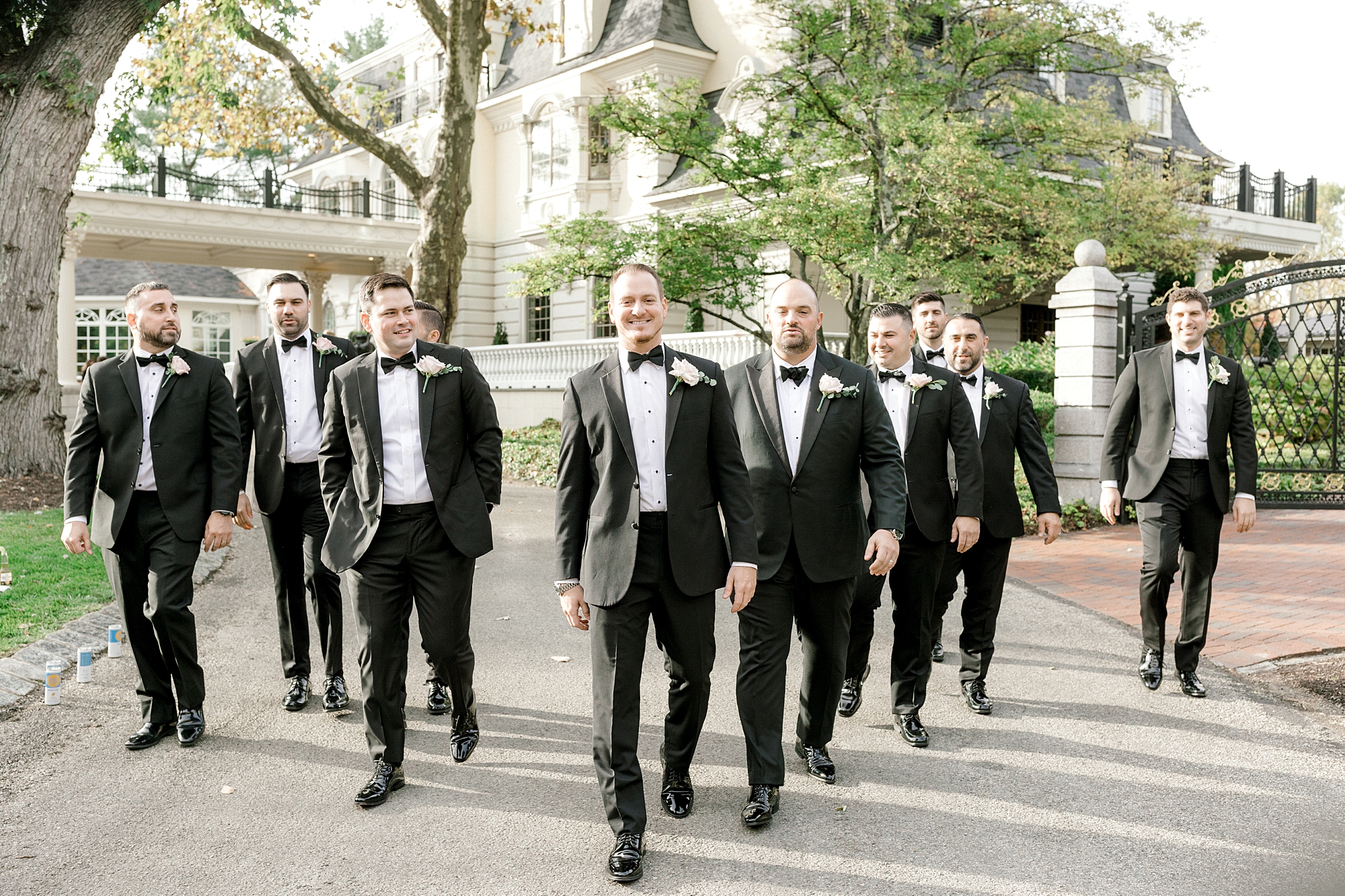 groom walks with groomsmen in tuxes outside the Ashford Estate