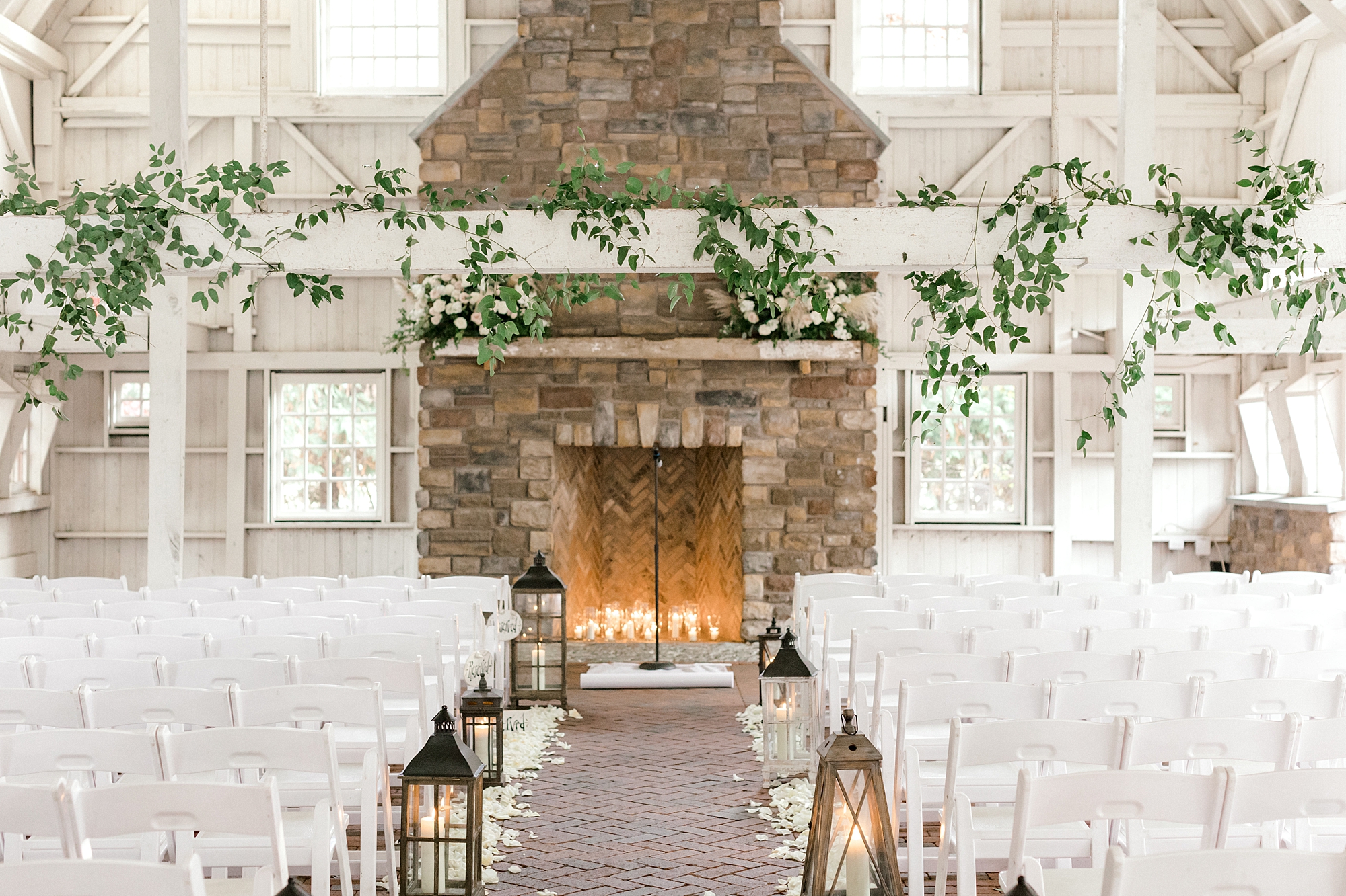 ceremony inside the Ashford Estate with fireplace and greenery wrapped on white beams