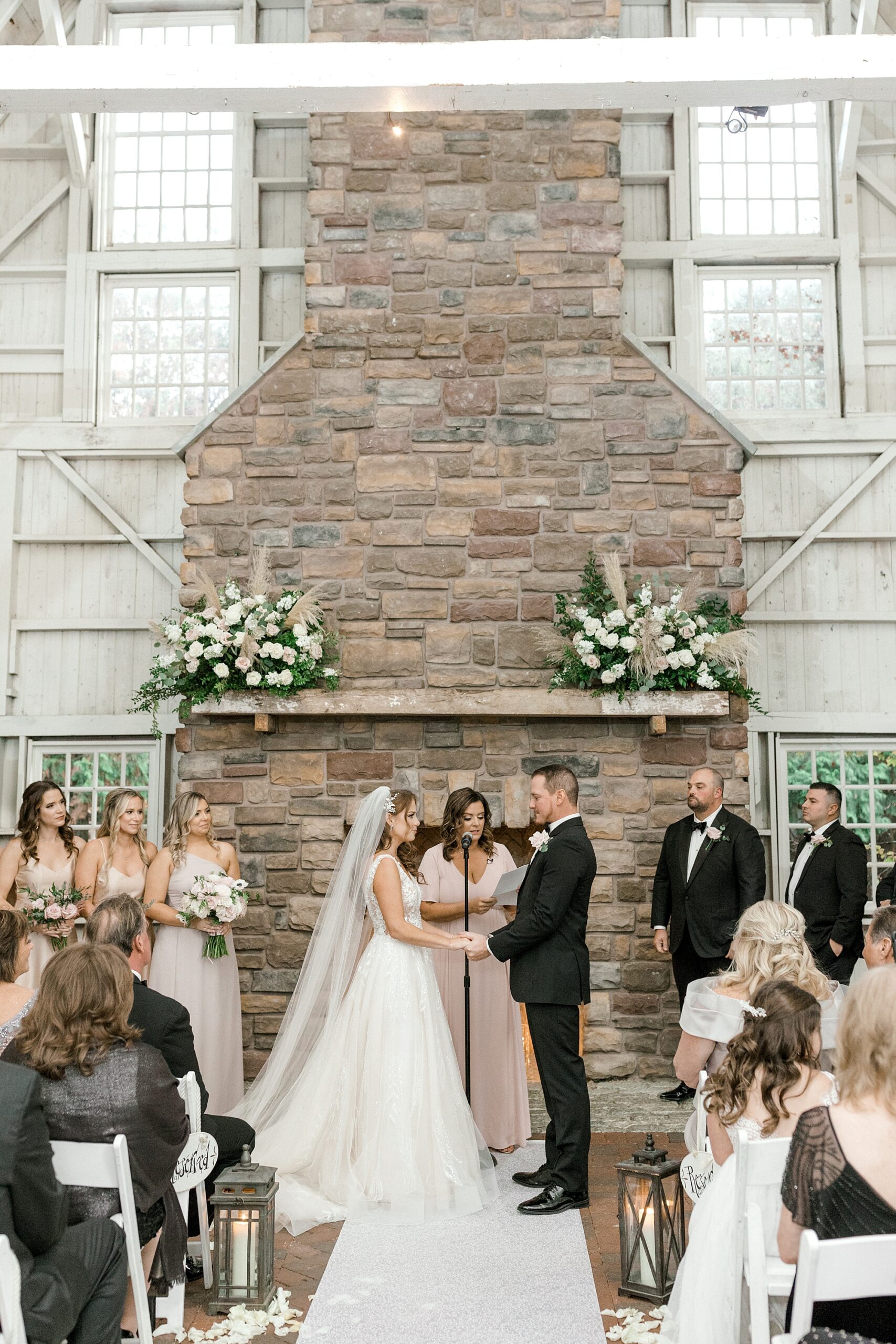 bride and groom hold hands by stone fireplace during ceremony