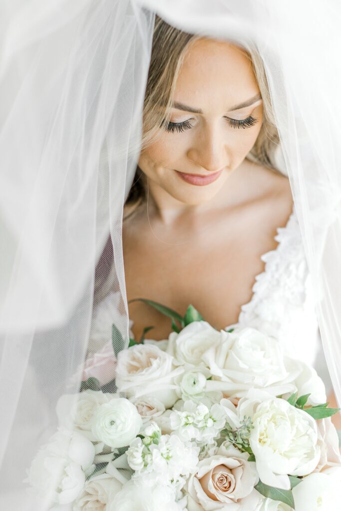 bride looks down at bouquet with white roses and duty pink flowers 