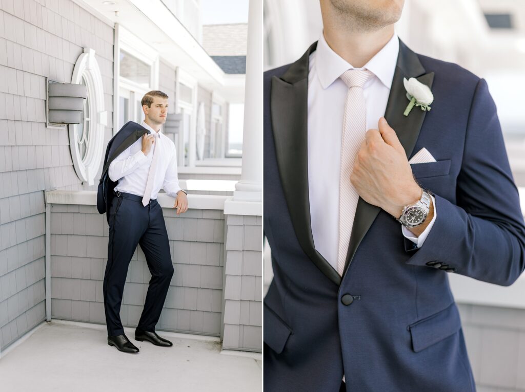 groom poses against wall at home with navy jacket over shoulder 