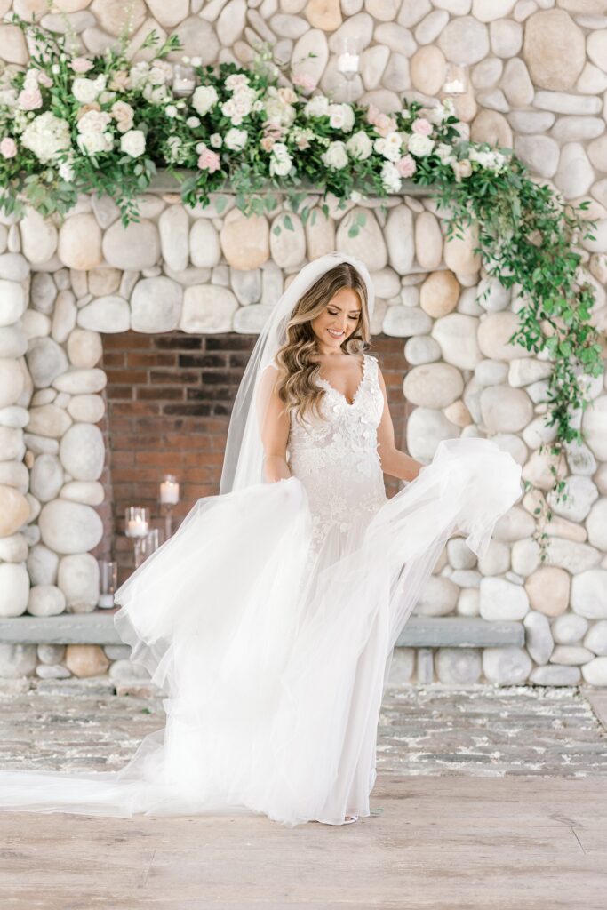 bride twirls in wedding dress by stone fireplace at Bonnet Island Estate
