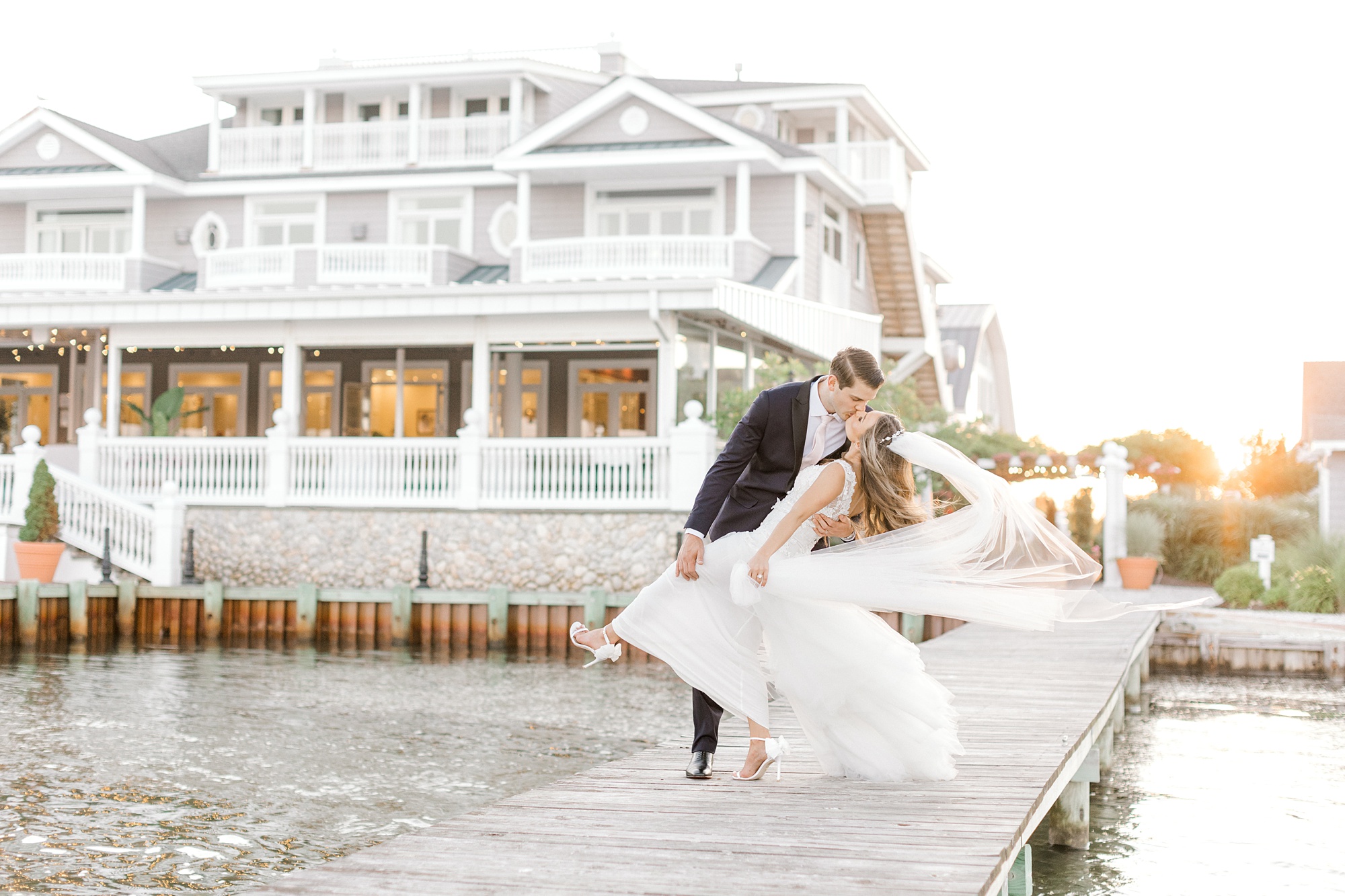 bride and groom kiss on dock at sunset in front of Bonnet Island Estate