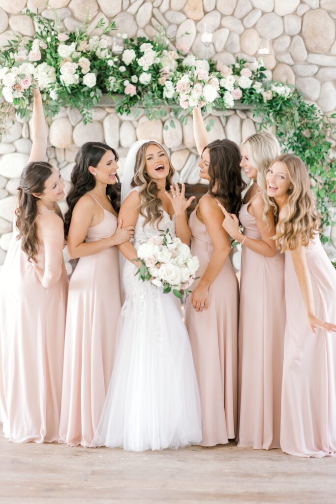 bride laughs with bridesmaids showing off wedding ring 