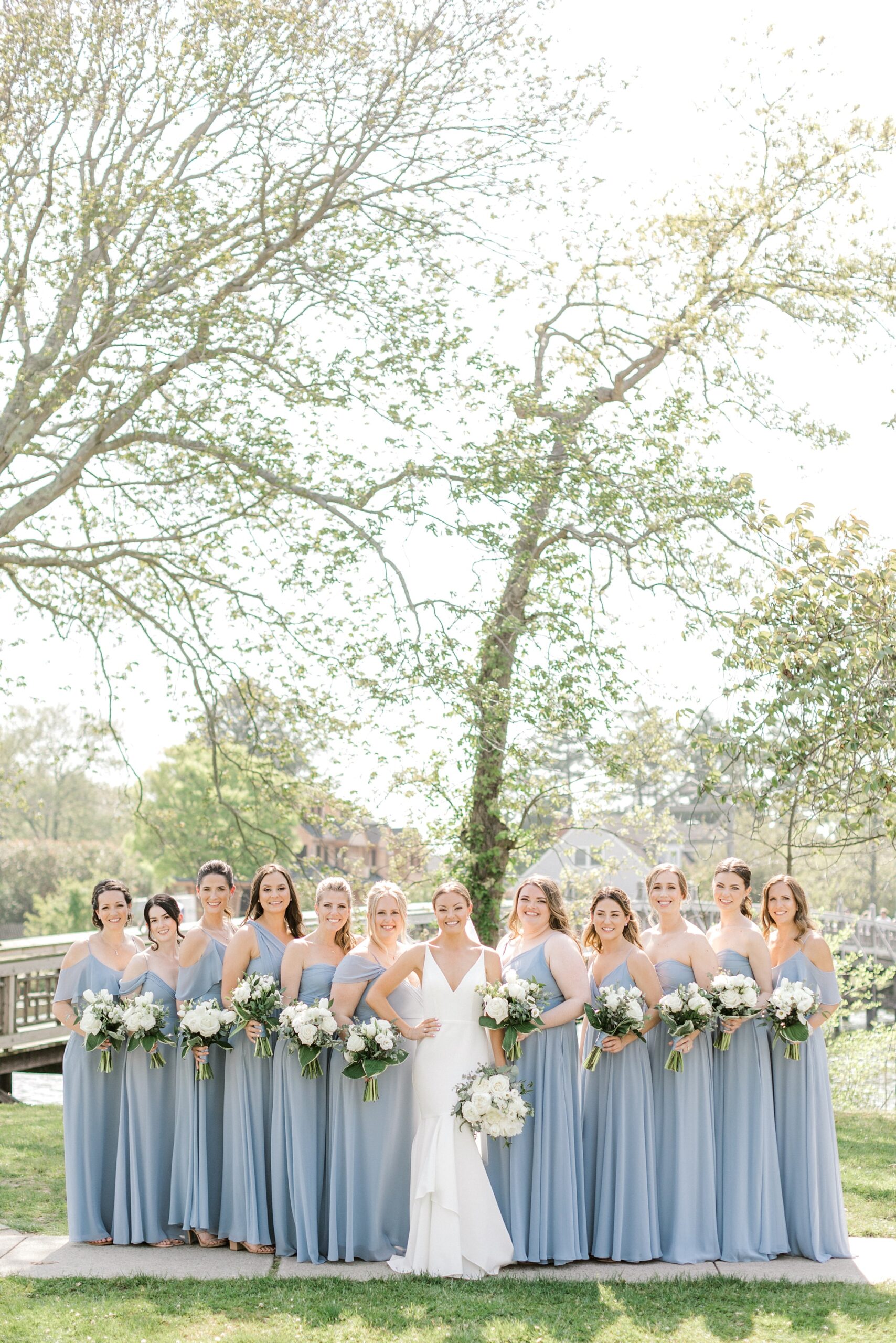 bride stands with bridesmaids in dusty blue gowns in Spring Lake NJ