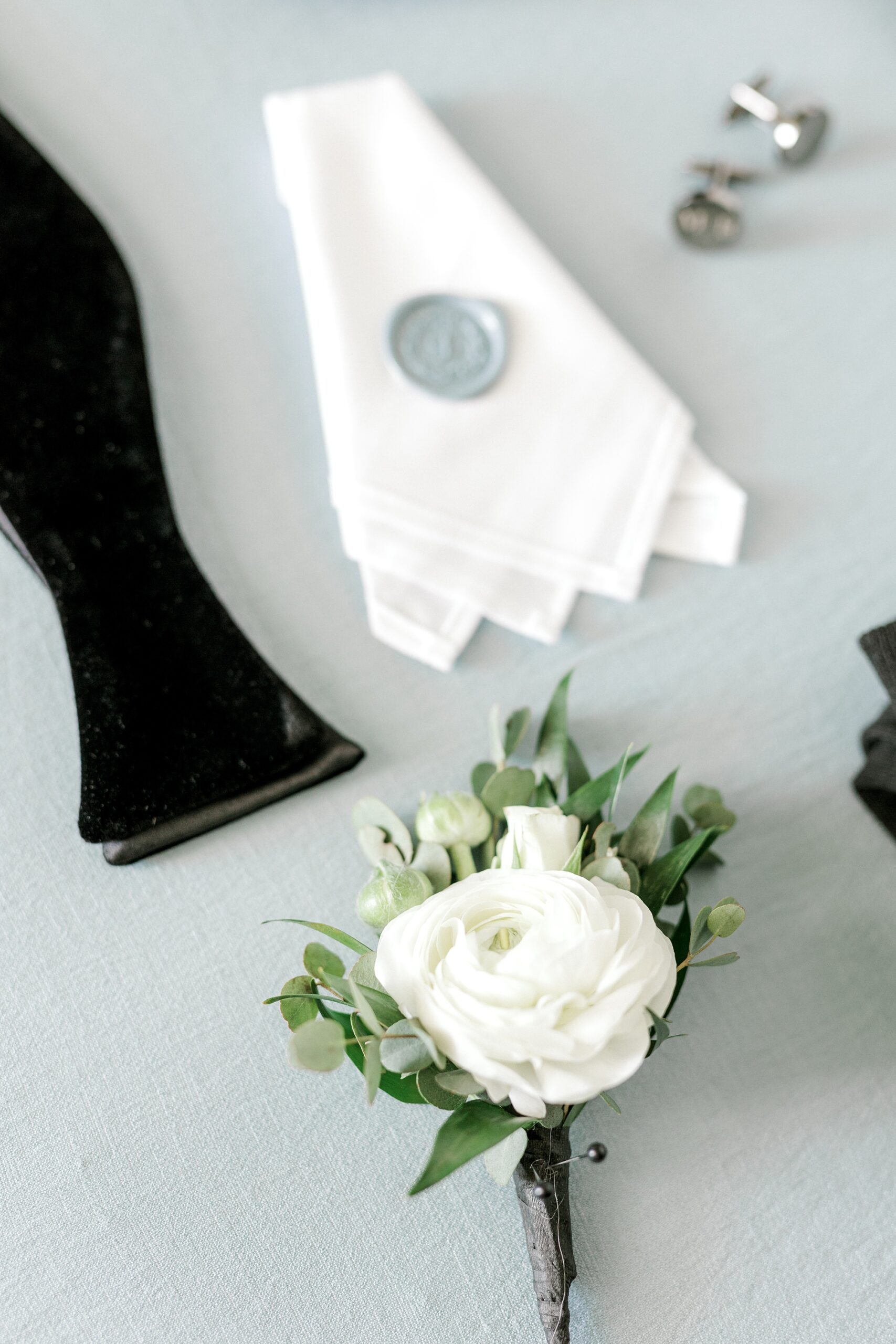groom's details on blue backdrop with white boutonniere