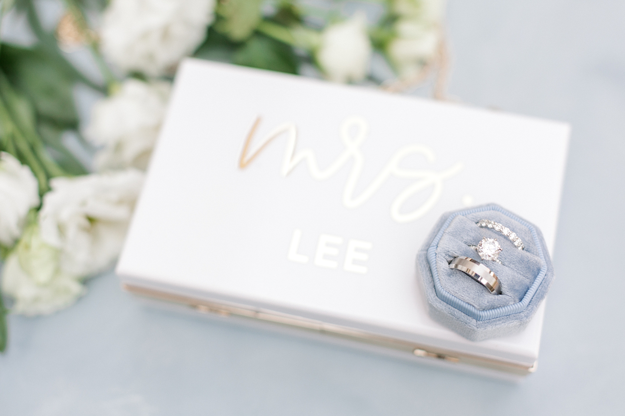 bride's rings in light blue box rest on jewelry box with MRS on top