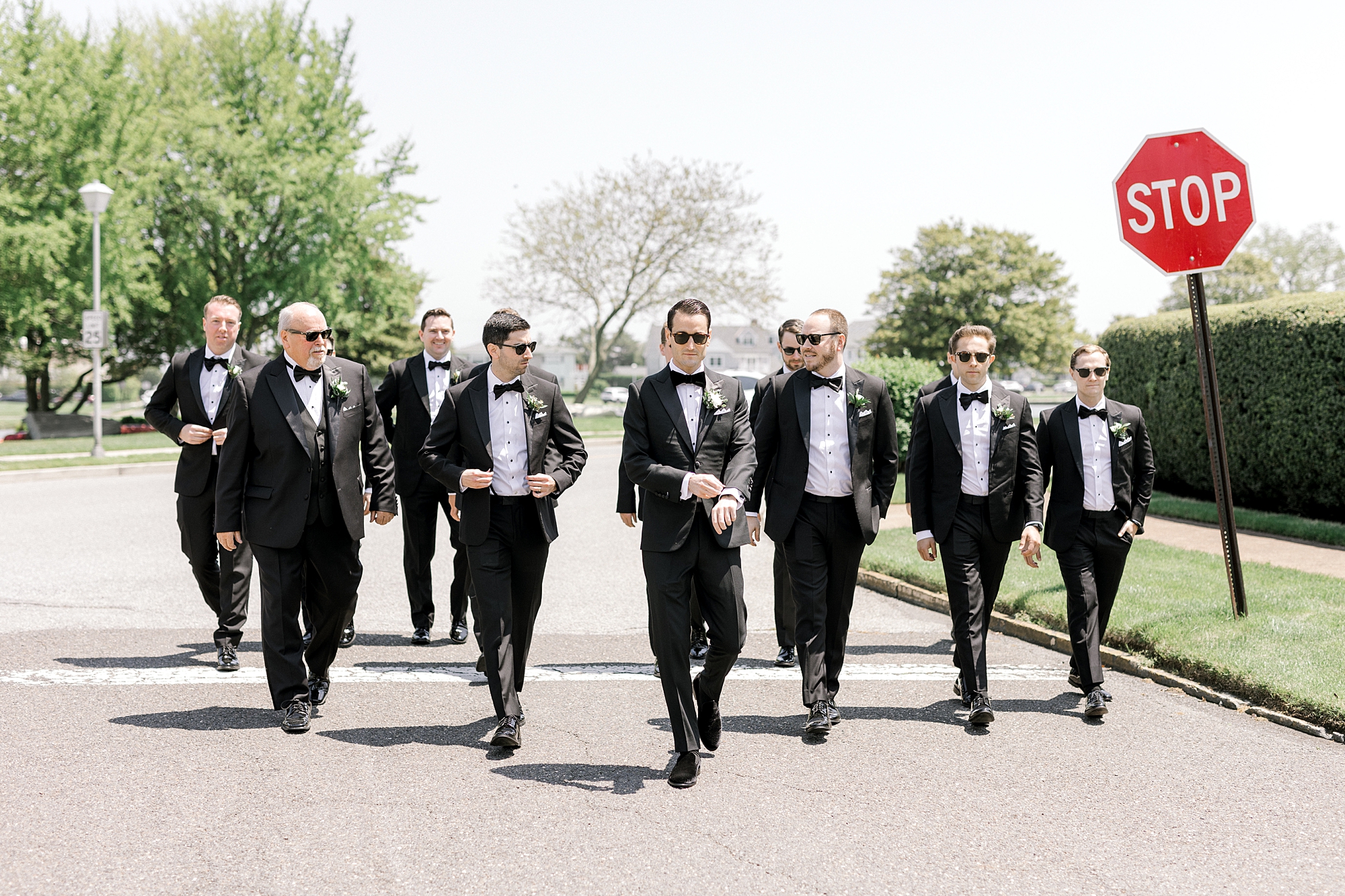 groom and groomsmen in black suits and sunglasses walk on street