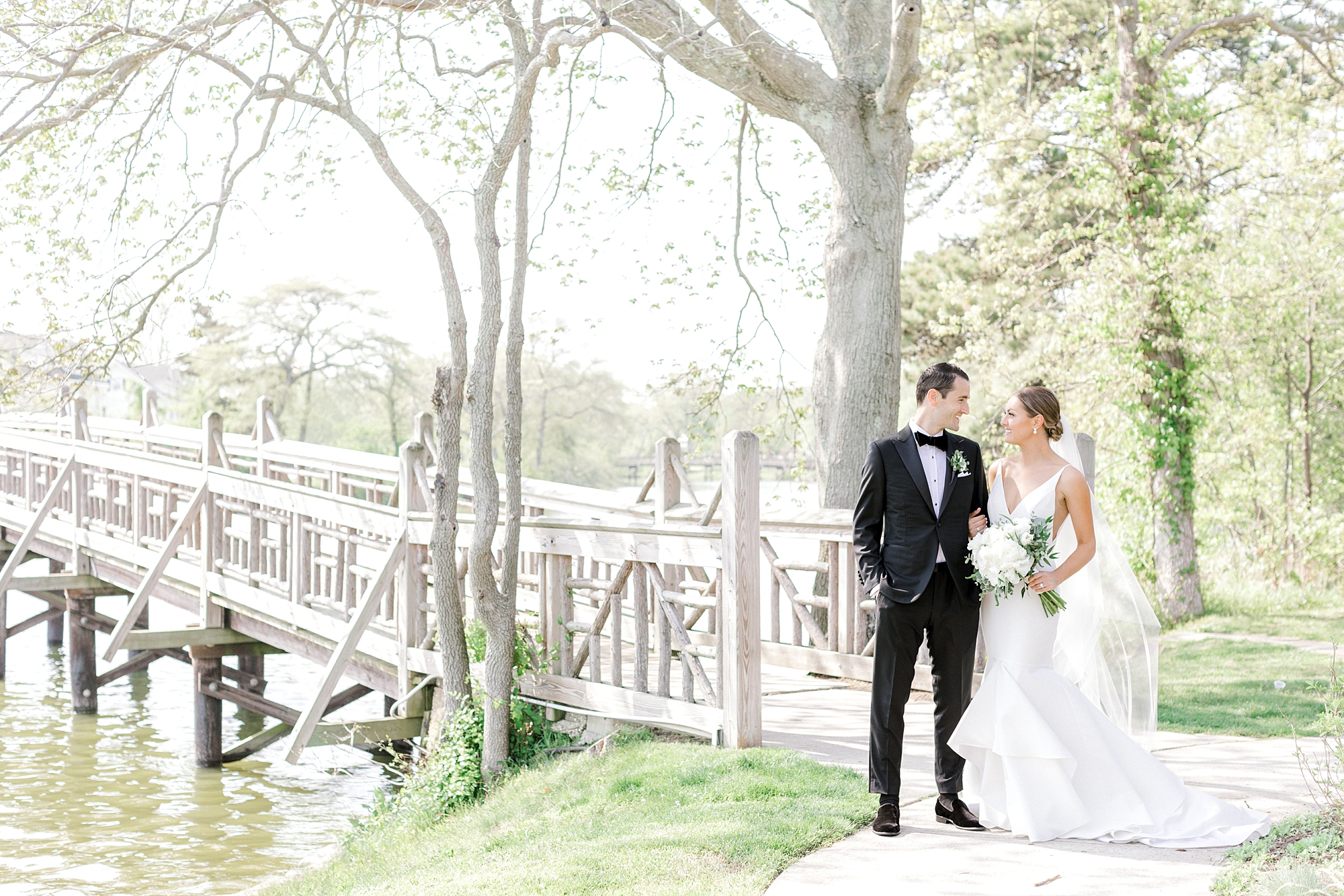 bride and groom pose by wooden bridge in Spring Lake Park