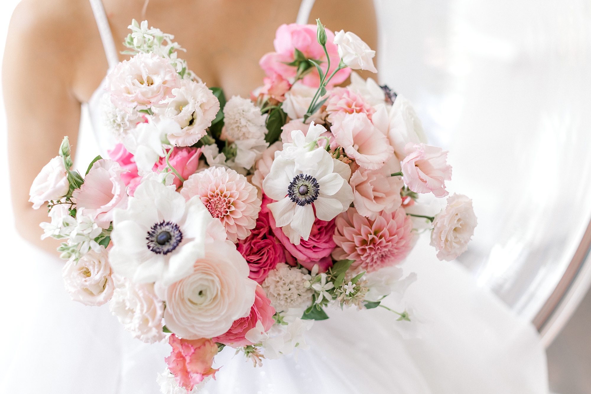 bride holds bouquet of pink flowers and anemones