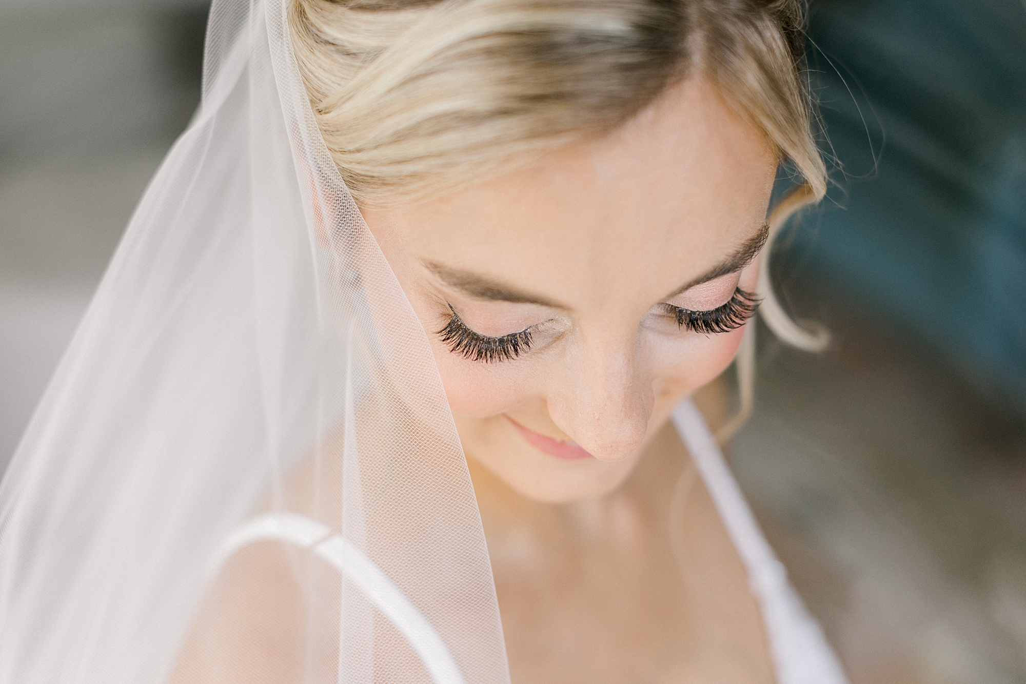 blonde bride looks down over shoulder with veil around her
