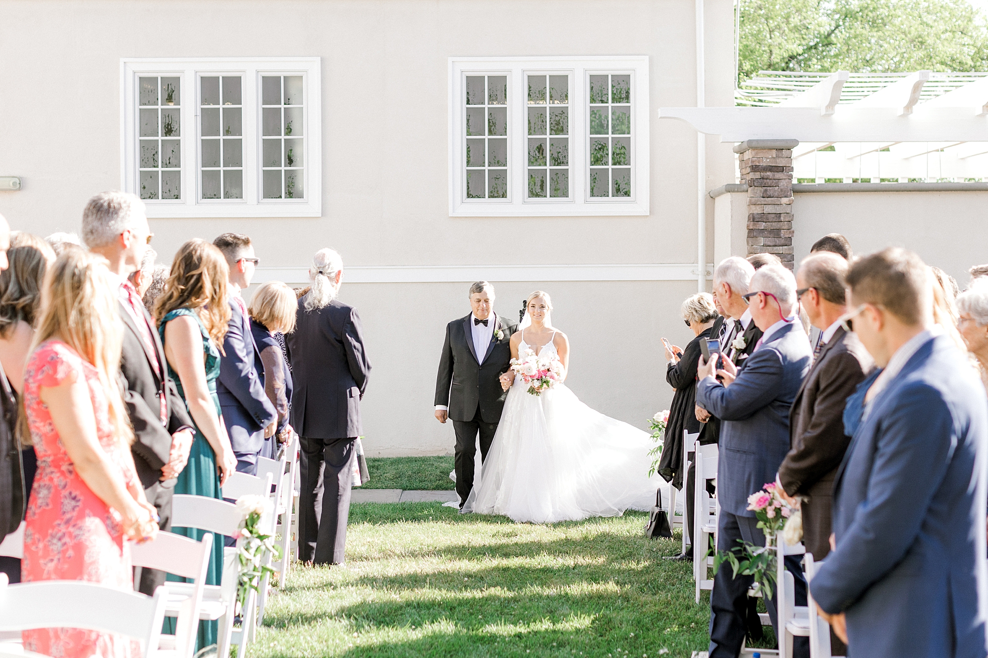 bride walks down aisle with dad for ceremony on lawn at Ryland Inn