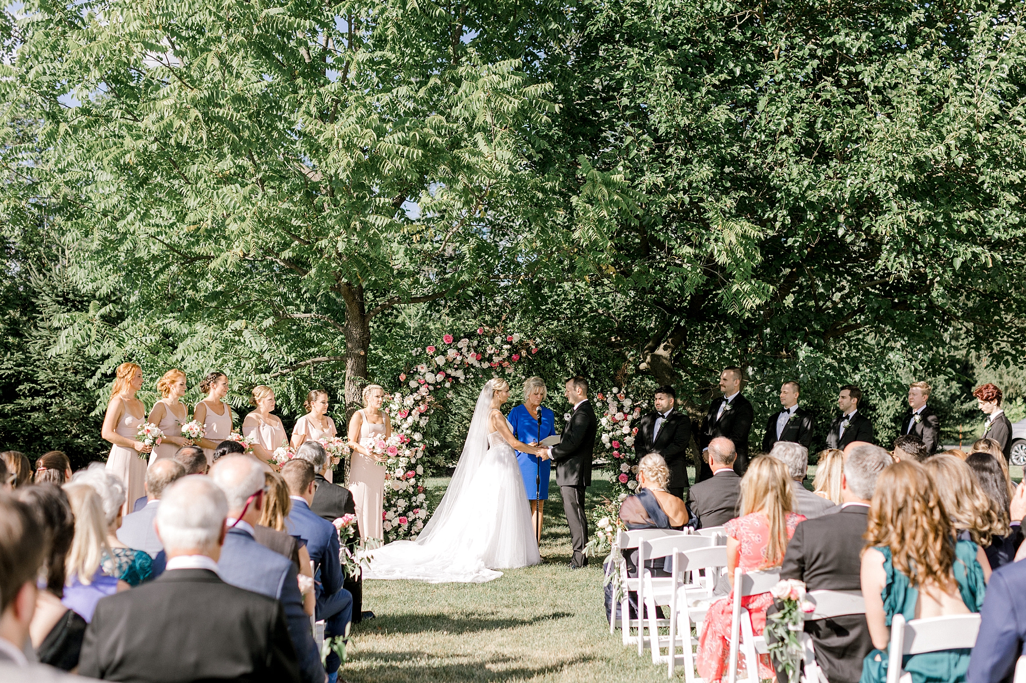 newlyweds hold hands during wedding ceremony on lawn at Ryland Inn