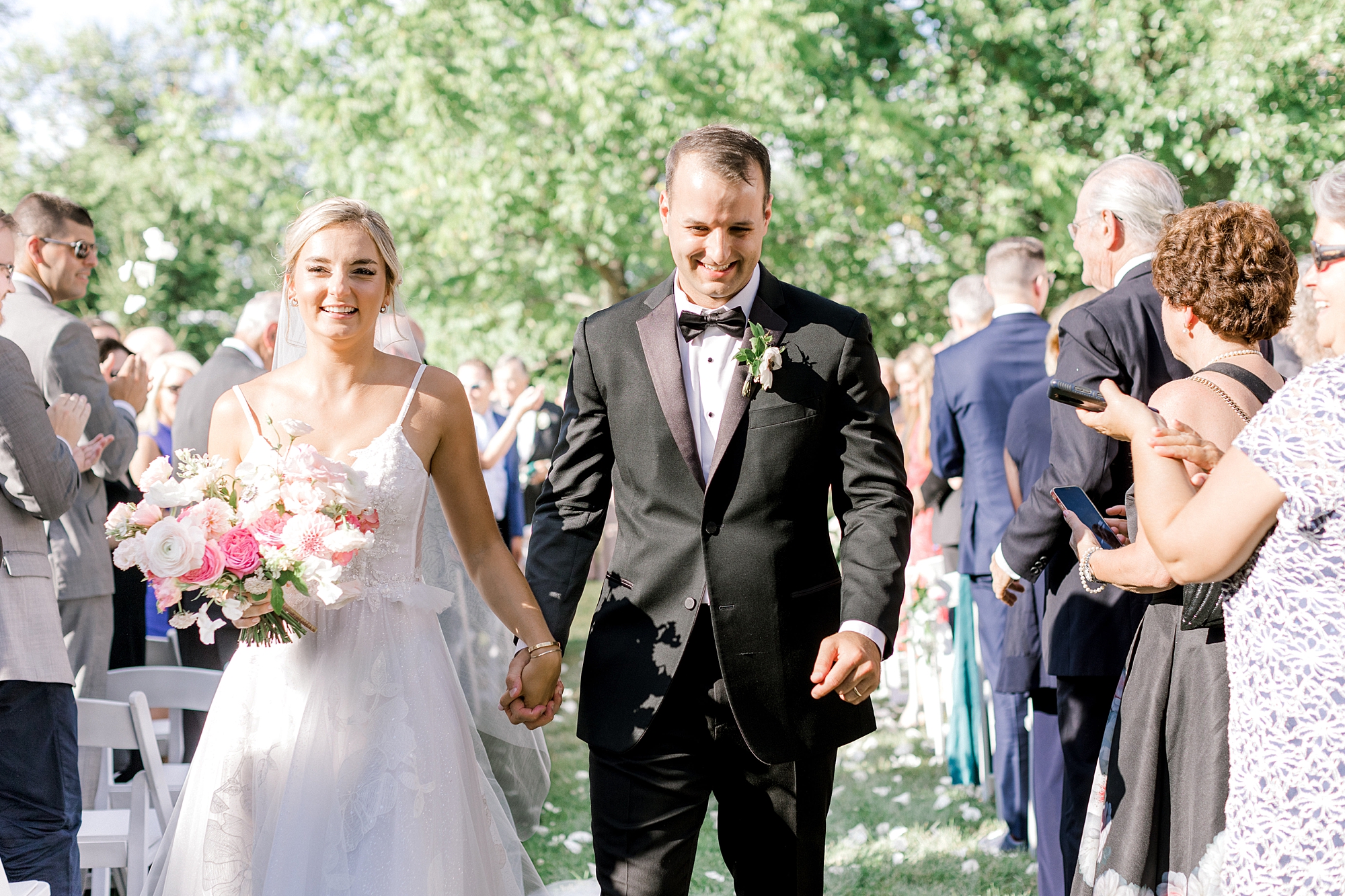bride and groom hold hands walking up aisle after ceremony