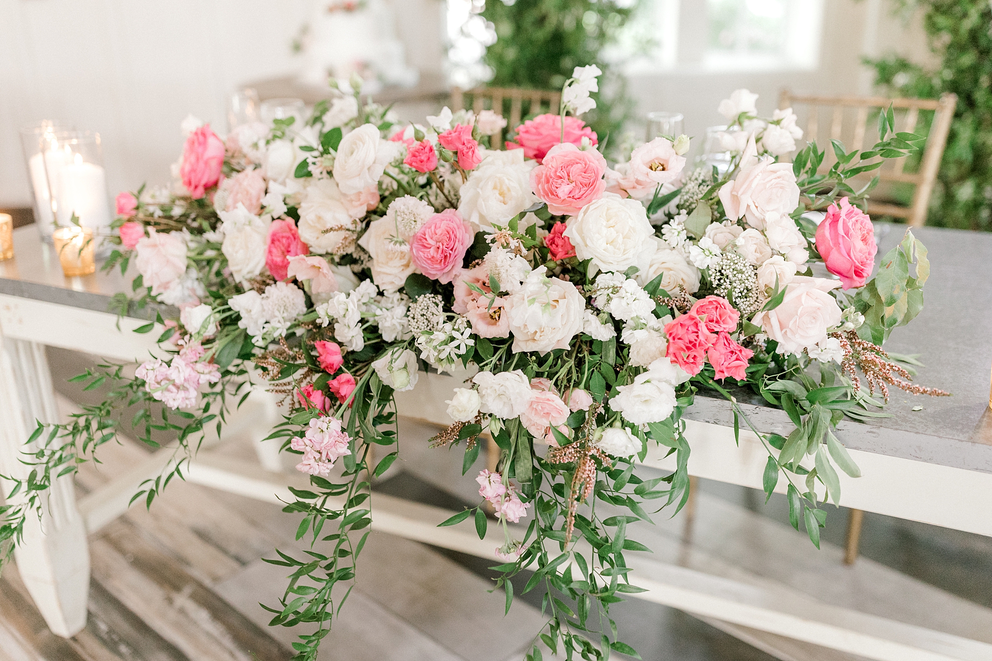 pink and white floral arrangement sits on edge of white table