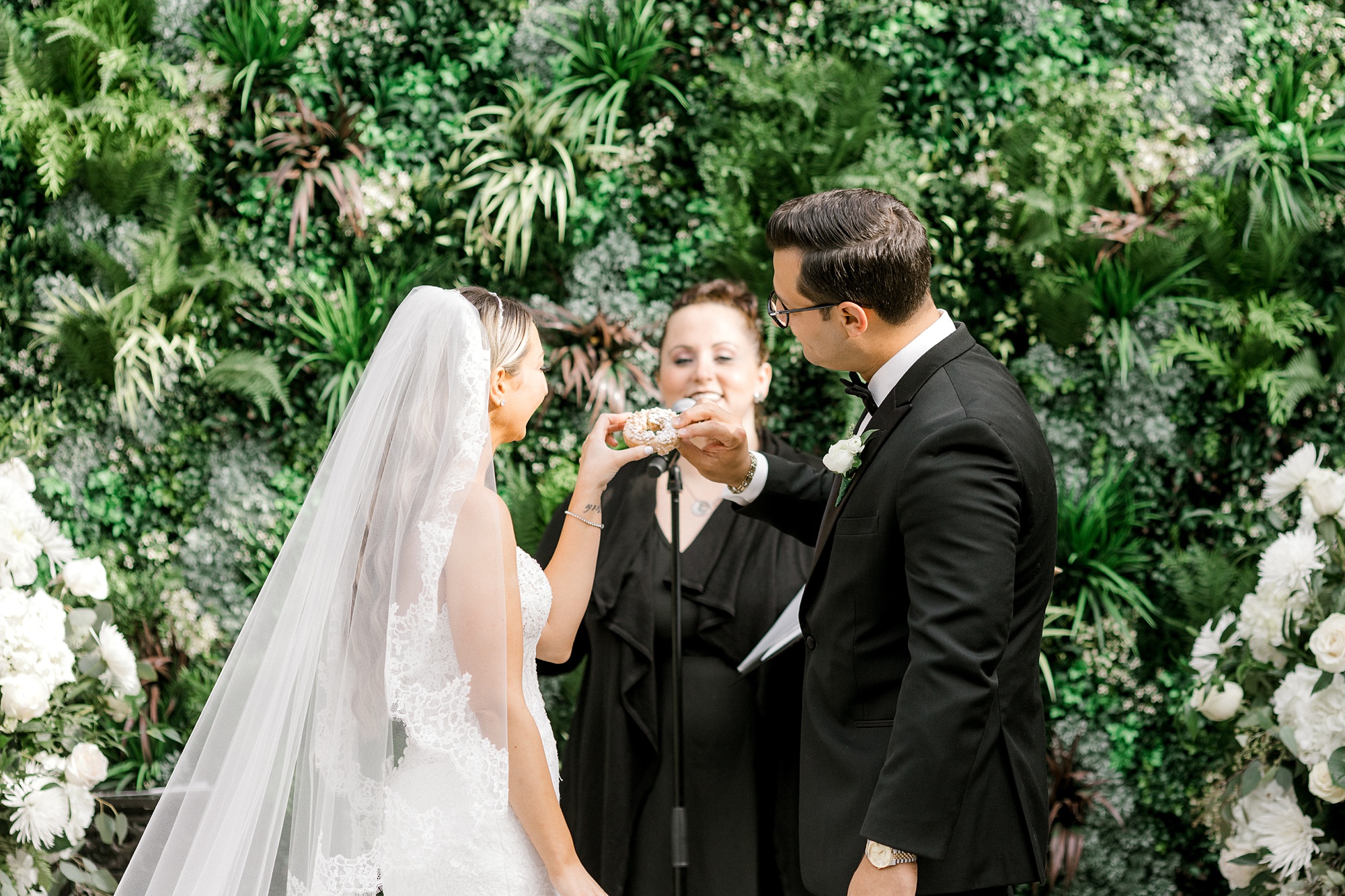 bride and groom share donut during wedding ceremony at The Refinery at Perona Farms