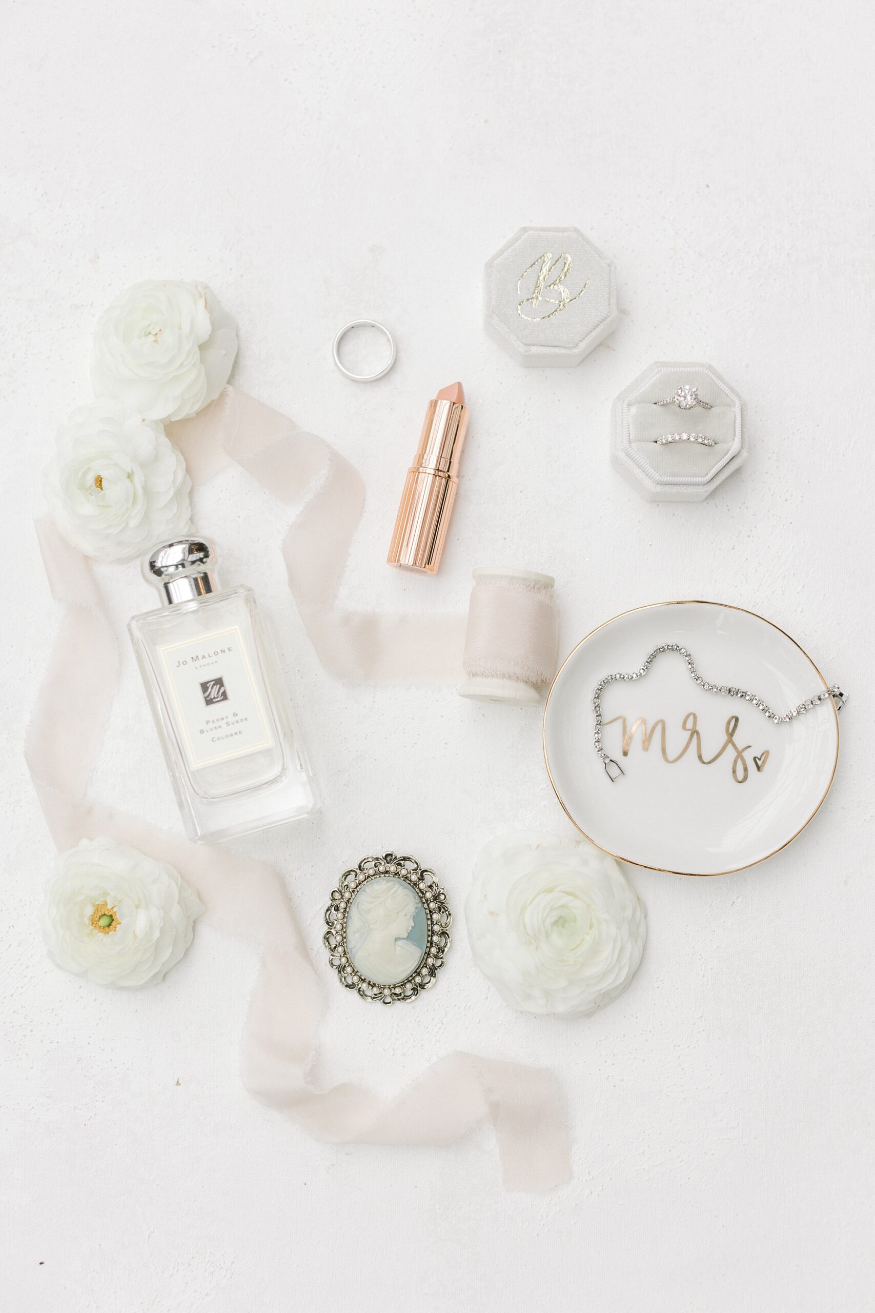 flatlay of bride's perfume, ribbon, and jewelry