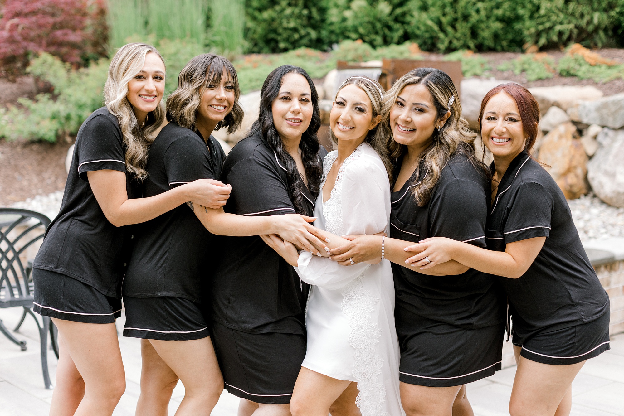 bride and bridesmaids hug in matching black an white pajamas