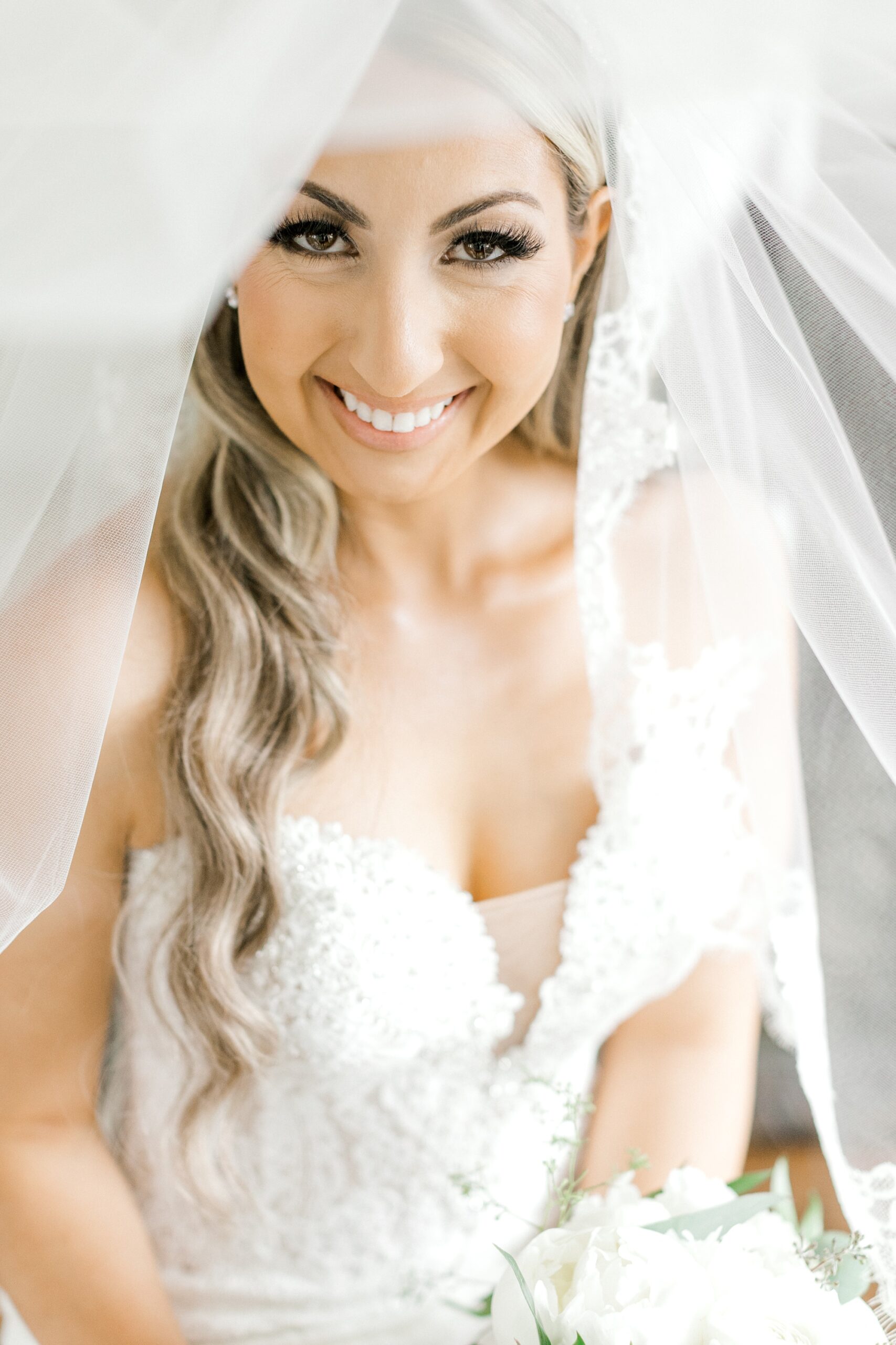 bride smiles under veil in strapless wedding gown