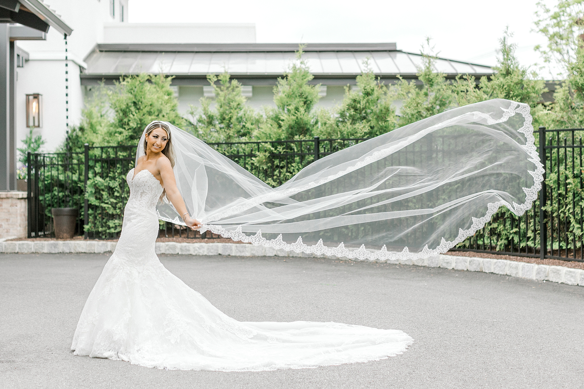 bride poses in wedding gown with veil floating behind her