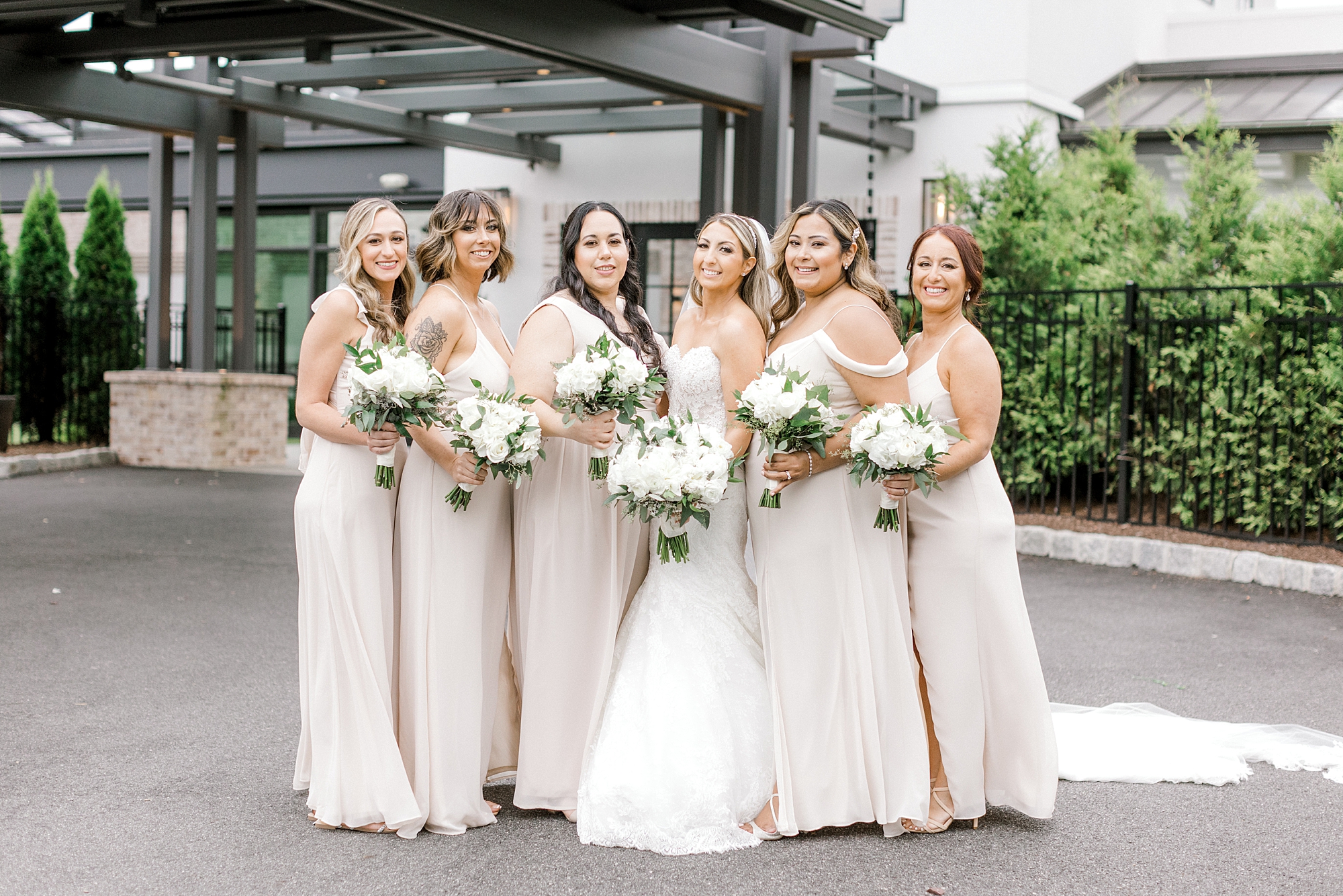 bride poses with bridesmaids in champagne gowns outside The Refinery at Perona Farms