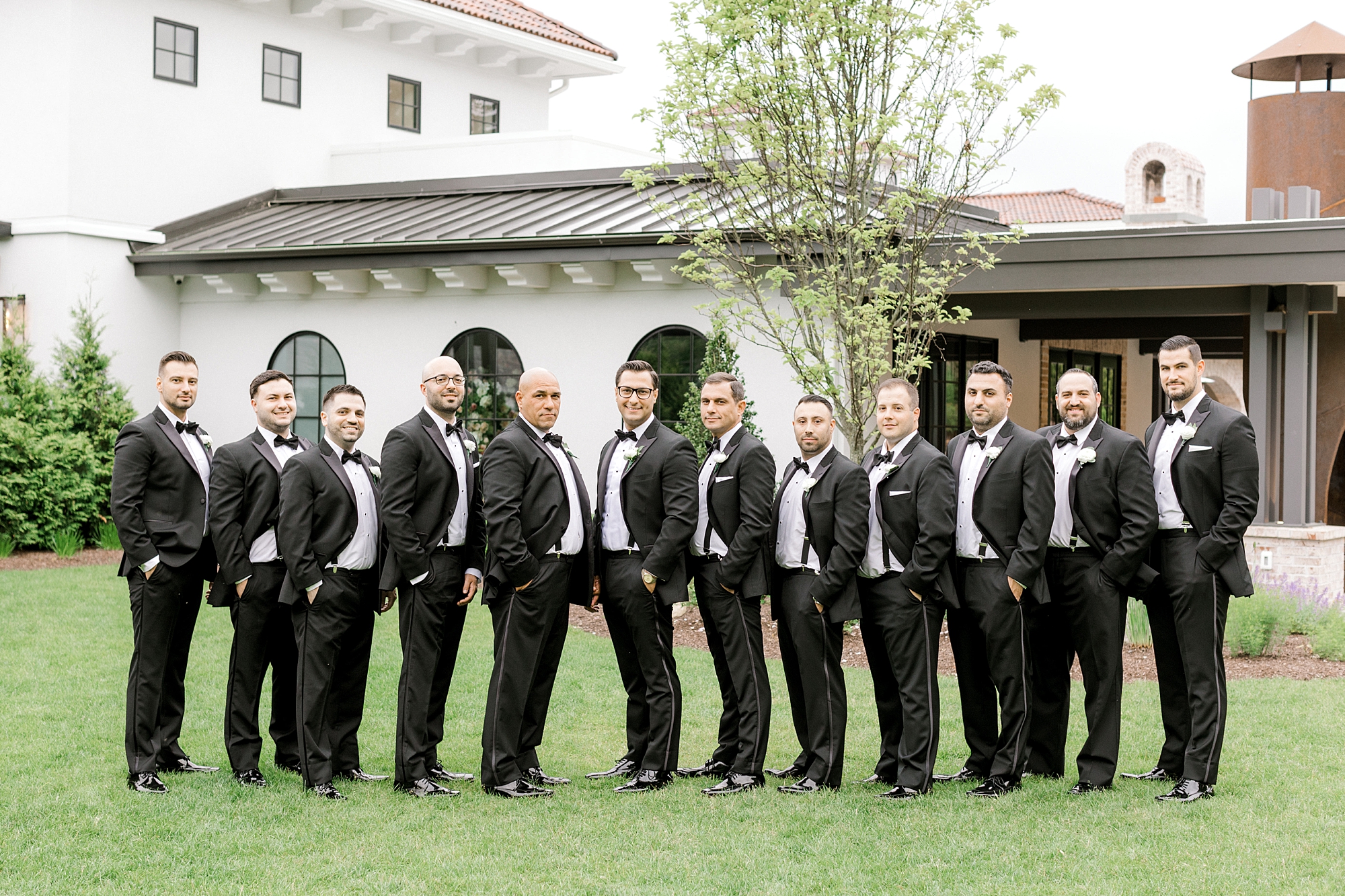 groom stands on lawn with groomsmen at The Refinery at Perona Farms
