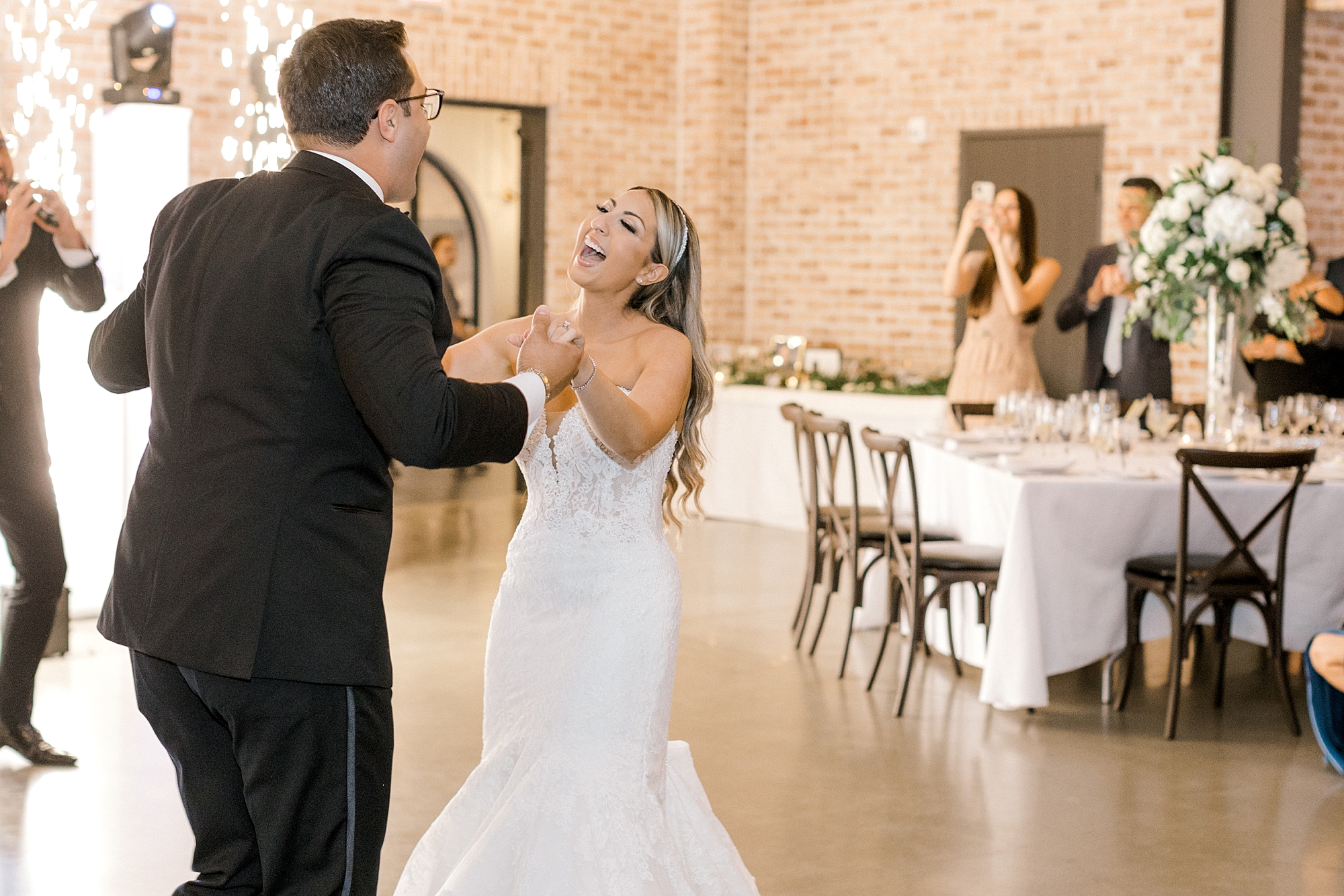 bride laughs while groom twirls her during reception dances