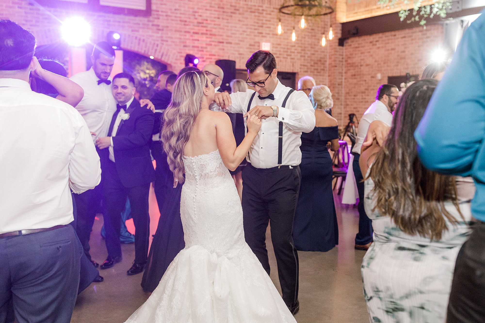 groom twirls bride on dance floor in white shirt and suspenders