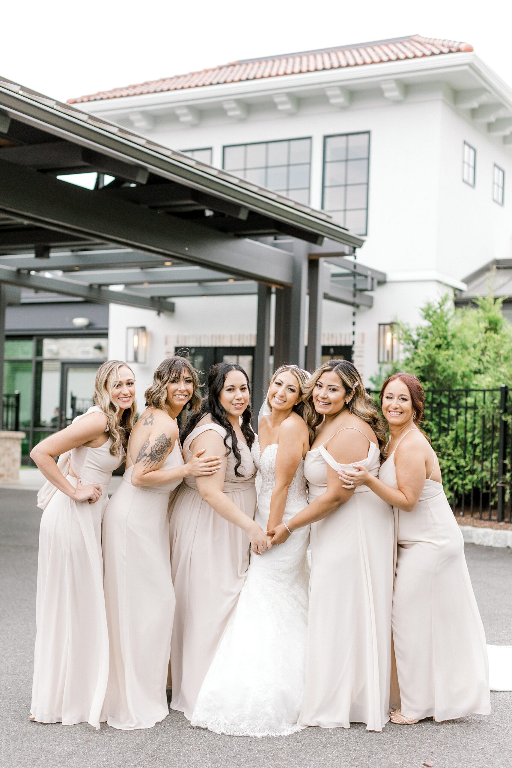 bride poses with bridesmaids in blush pink gowns outside The Refinery at Perona Farms