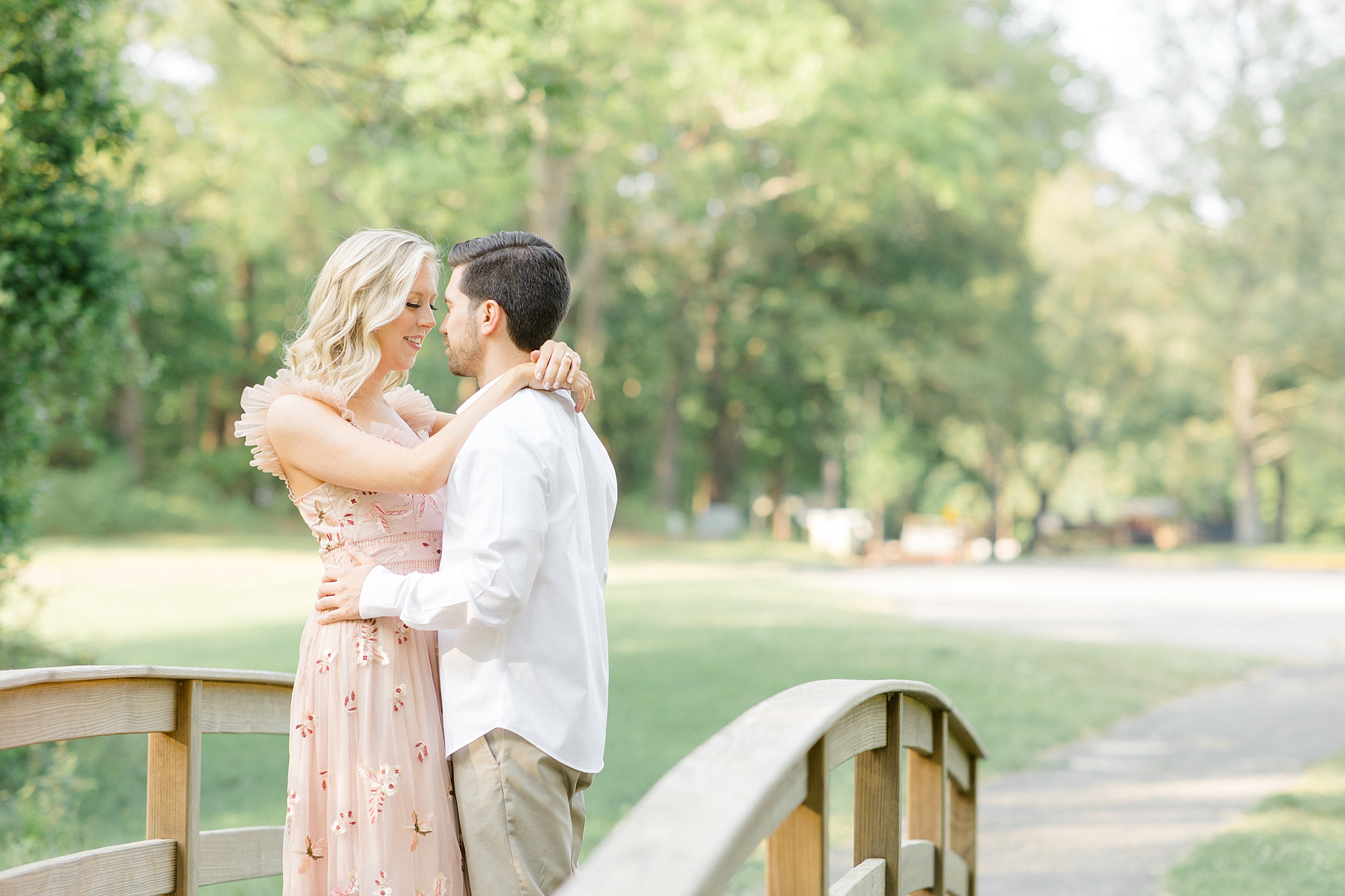 engaged couple hugs on wooden bridge in Allaire State Park