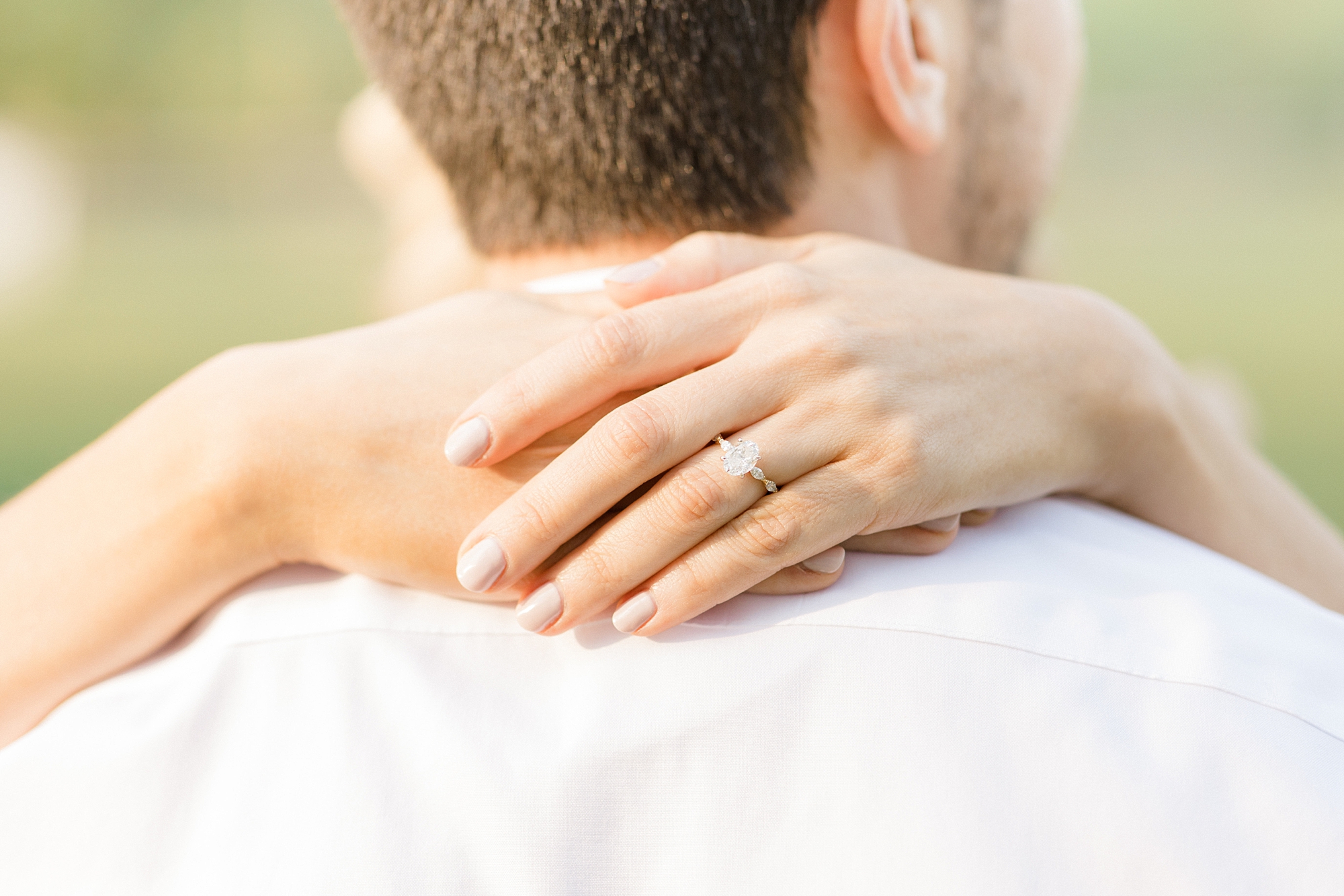 woman hugs man around neck showing engagement ring