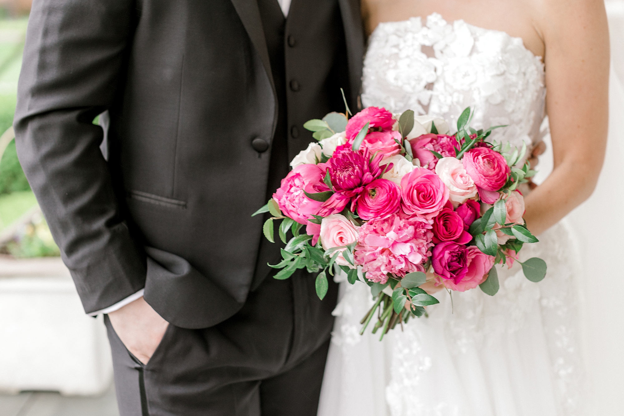 bride and groom hug while bride holds pink spring bouquet