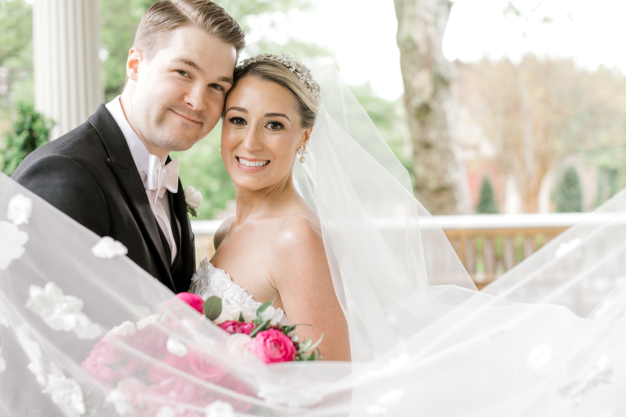 newlyweds lean heads together with veil around them on patio at the Ashford Estate