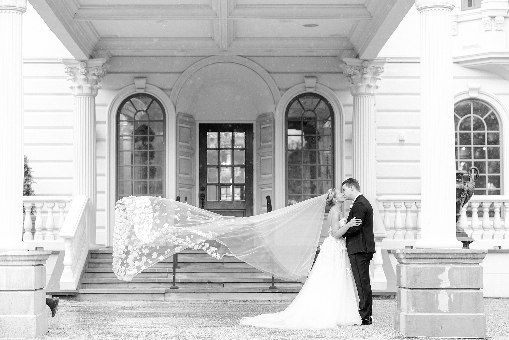 bride and groom kiss with bride's veil floating behind them outside the Ashford Estate