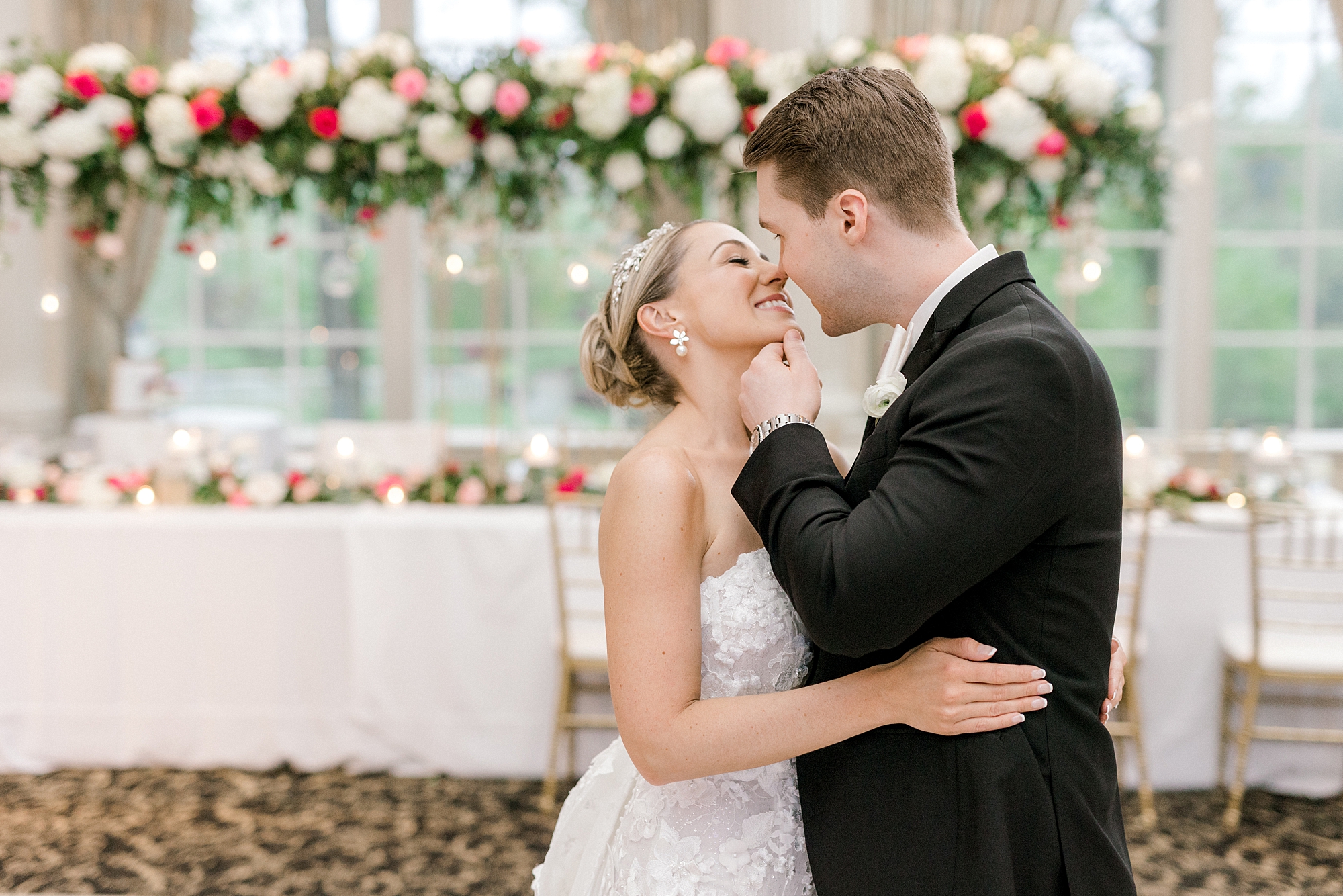 groom leans to kiss bride while holding her chin in front of reception table at the Ashford Estate