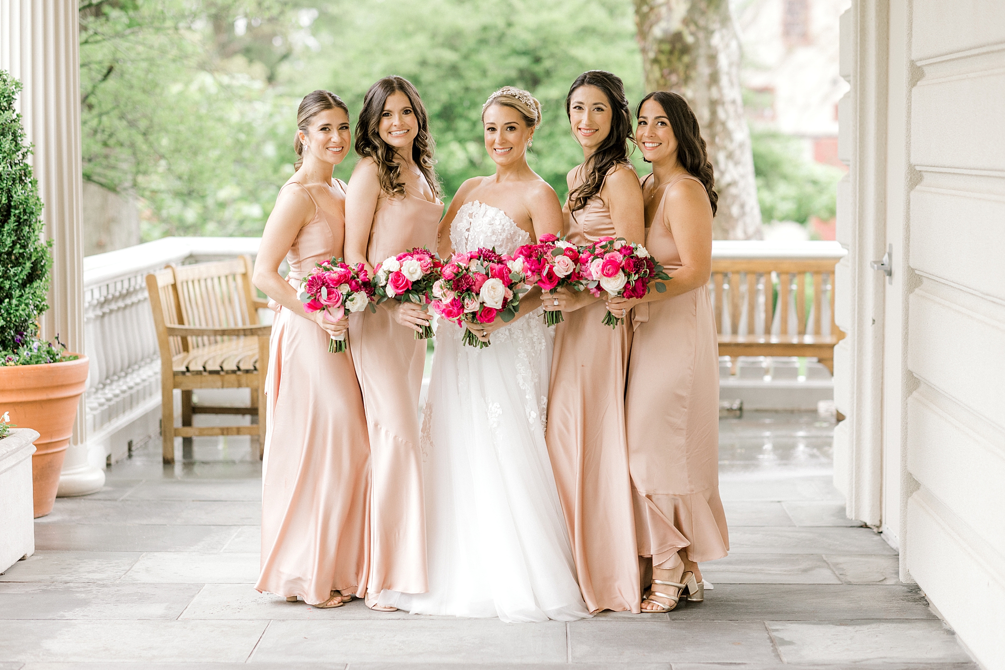 bride poses with four bridesmaids in blush gowns on the patio at The Ashford Estate