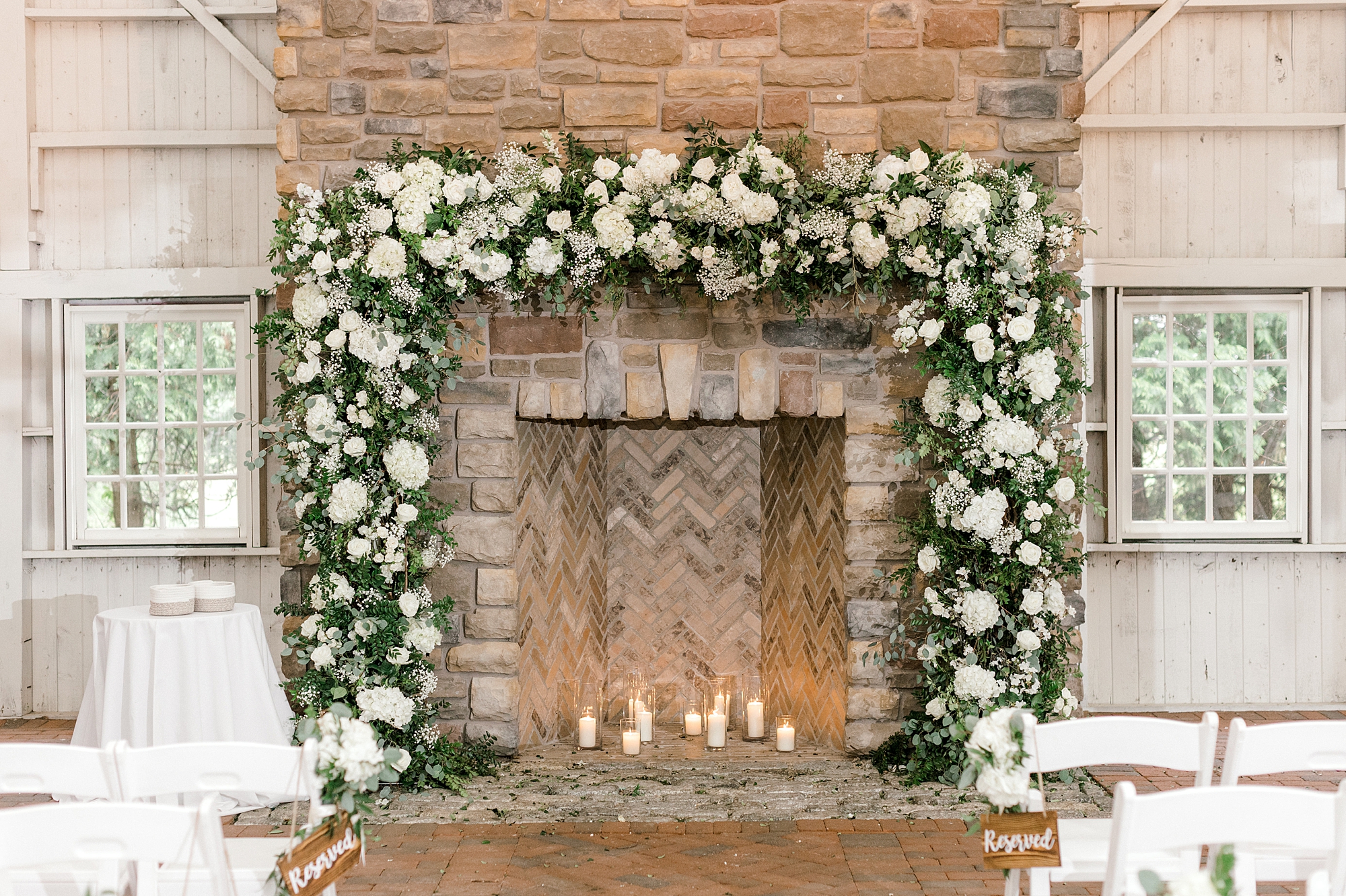 wedding ceremony setup with white and green garland laying over fireplace at The Ashford Estate