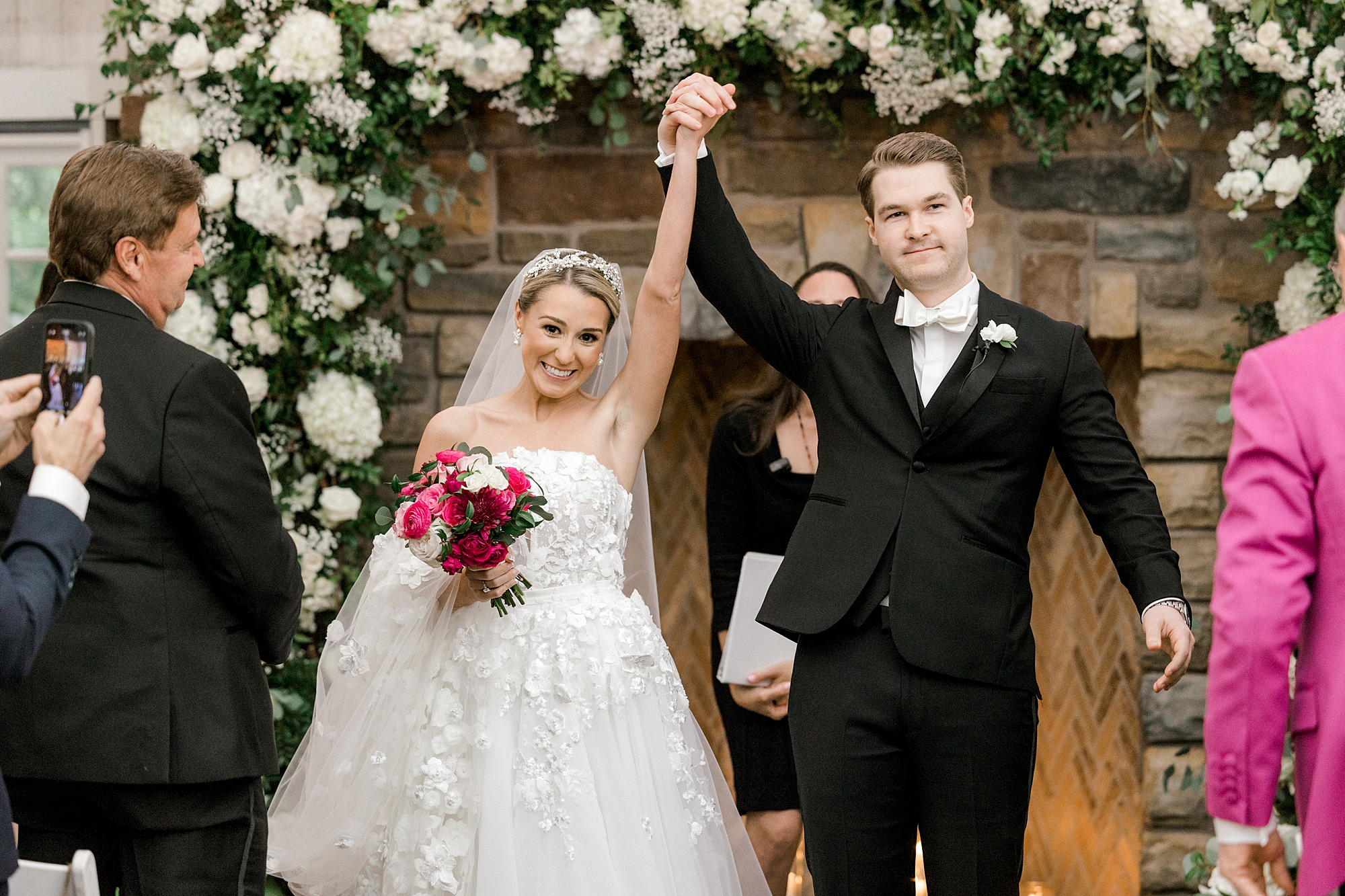newlyweds cheer holding hands up by fireplace after wedding ceremony