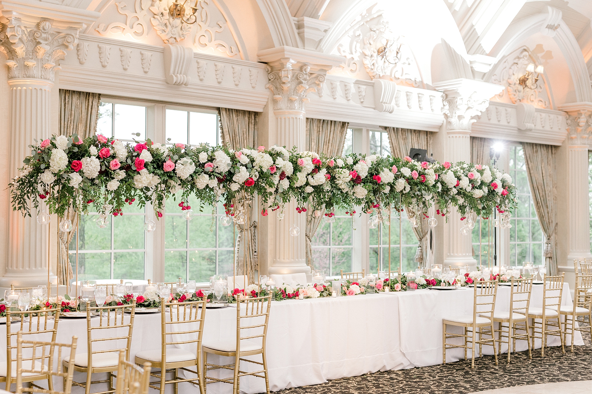 wedding reception tables with tall floral centerpieces of white and pink roses