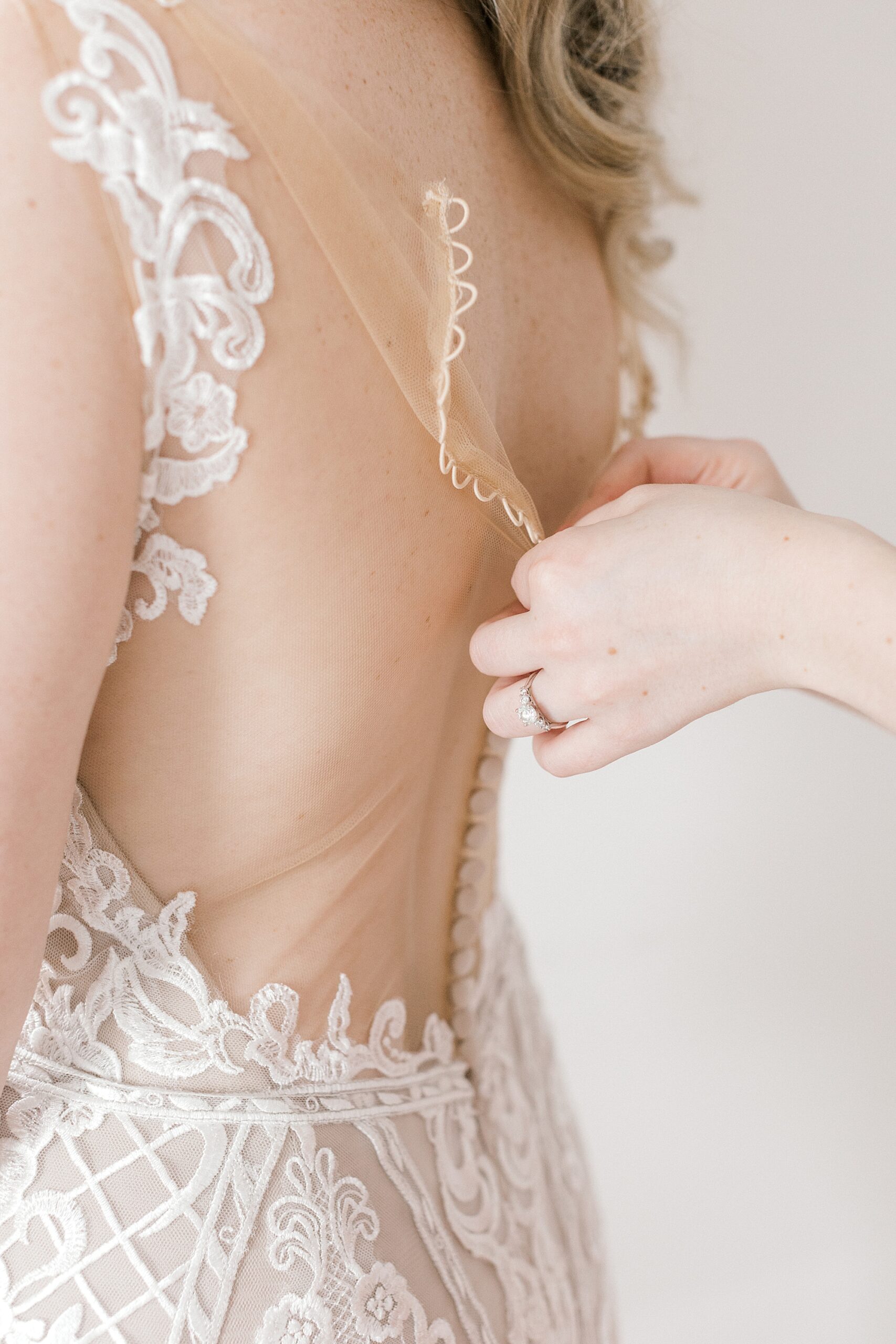woman buttons up bride's gown