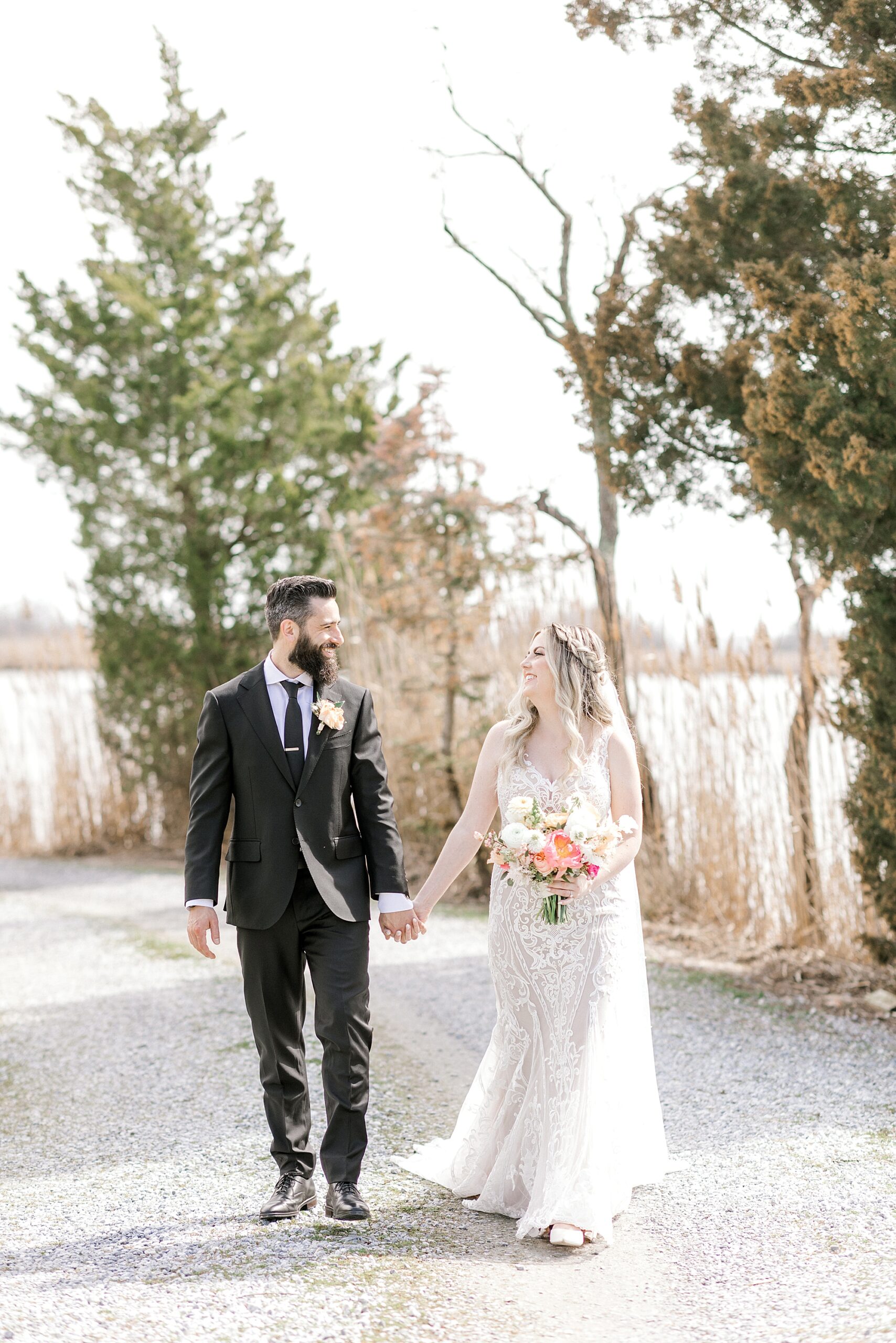 newlyweds hold hands walking down path near water at The Townsend Property