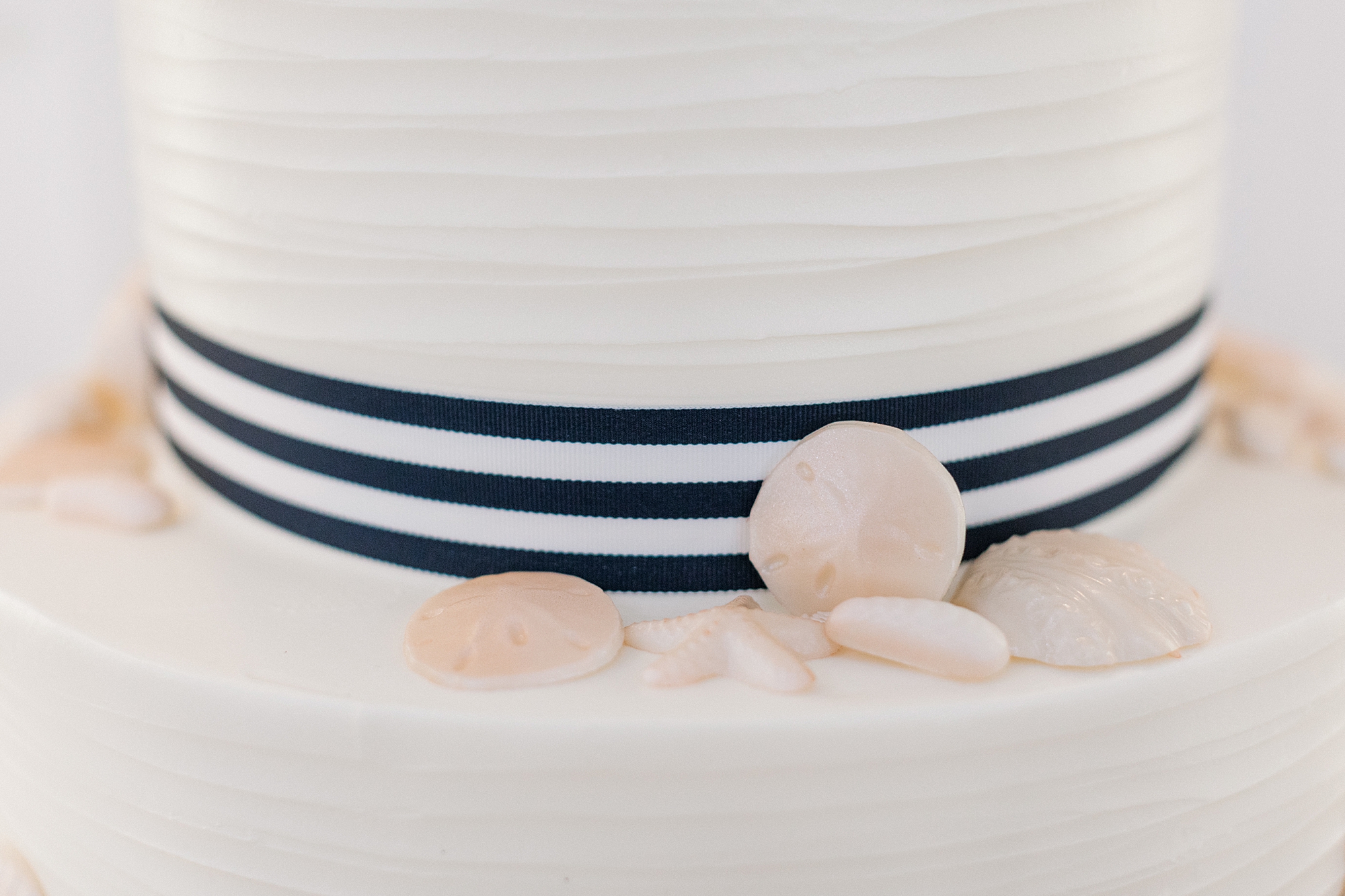 wedding cake with blue ribbon around center and seashells