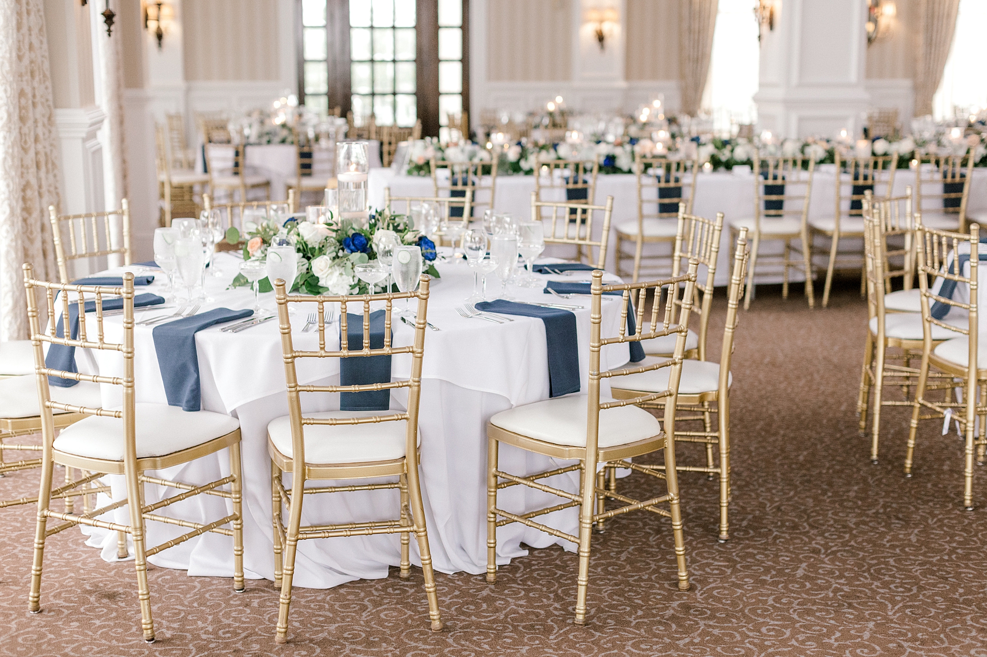 wedding reception at Mallard Island Yacht Club with white table cloths, navy napkins and gold chairs
